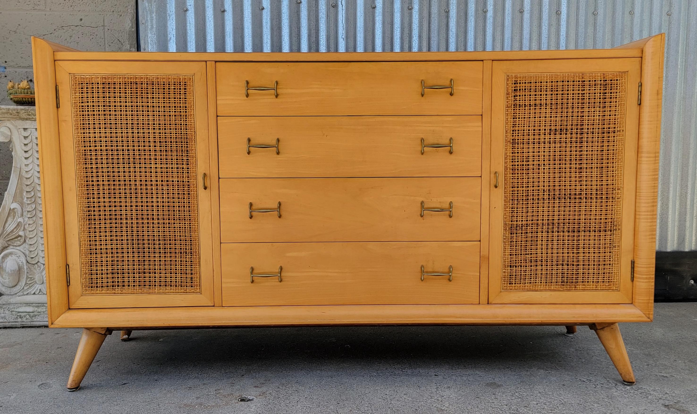 A 1950's Mid-Century Modern blonde credenza with cane door detail. Original condition with a beautiful glow to finish. Unique design in the manner of Paul McCobb. Solid wood materials and dovetail construction. A quality build with ample storage.