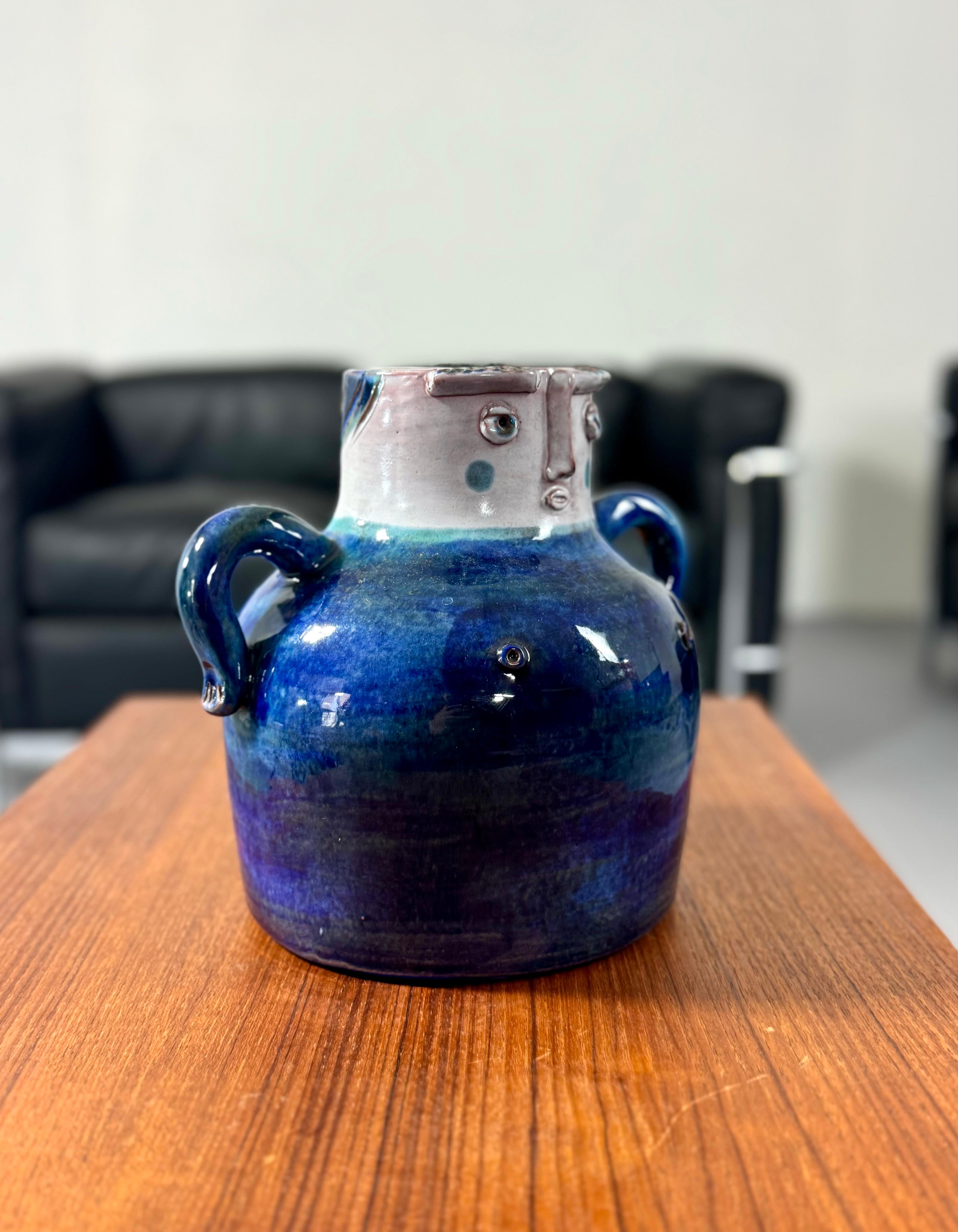 This extraordinary Mid-Century Modern vase, crafted by the renowned French brothers Robert and Jean Cloutier, combines masterful craftsmanship with a unique sculptural aesthetic. The vase is glazed in a mesmerizing gradient of blue, reminiscent of
