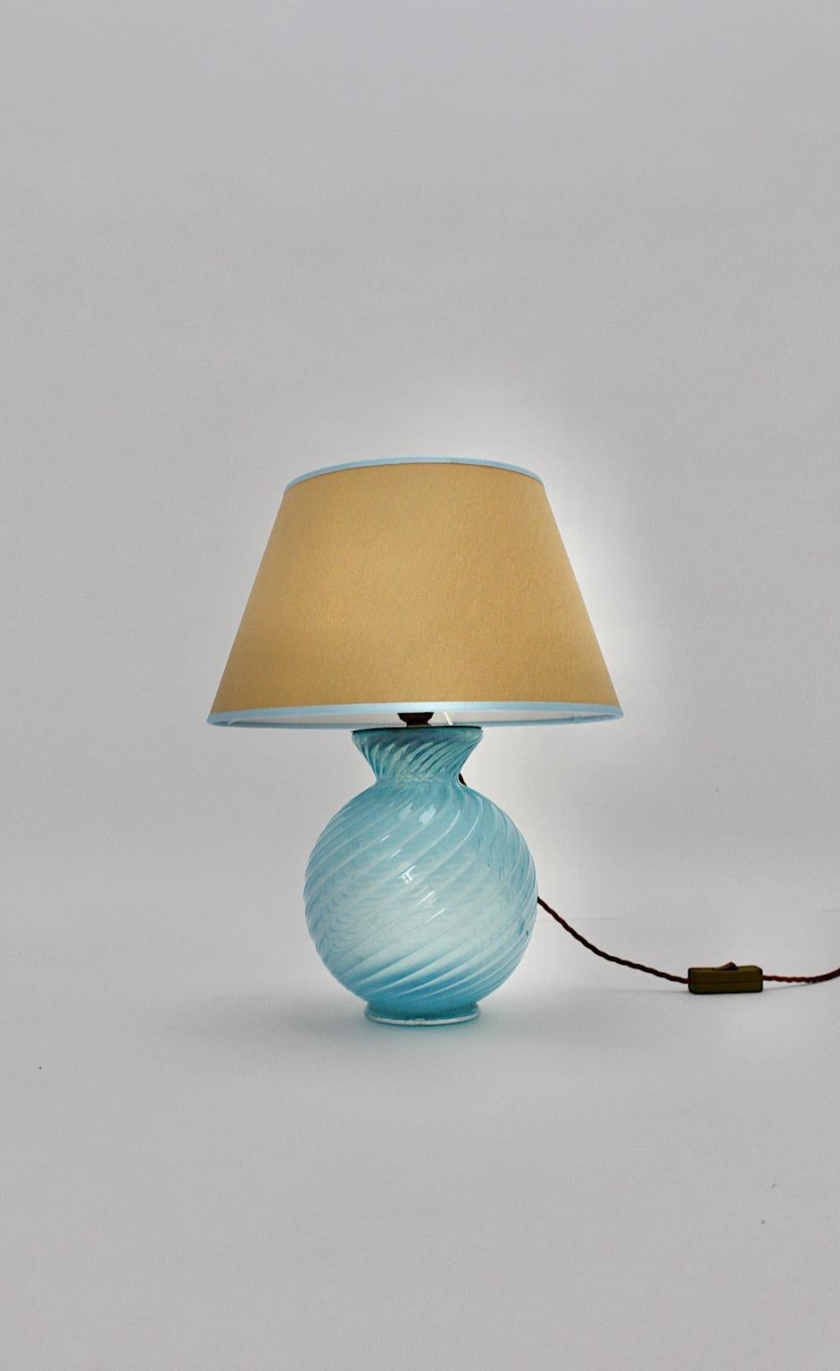 Mid Century Modern vintage pastel blue table lamp from hand made glass Barovier & Toso with a replaced lamp shade from golden fabric, Italy 190s.
A delicate and high-quality soft pastel blue vintage glass table lamp by Barovier & Toso, Italy with a