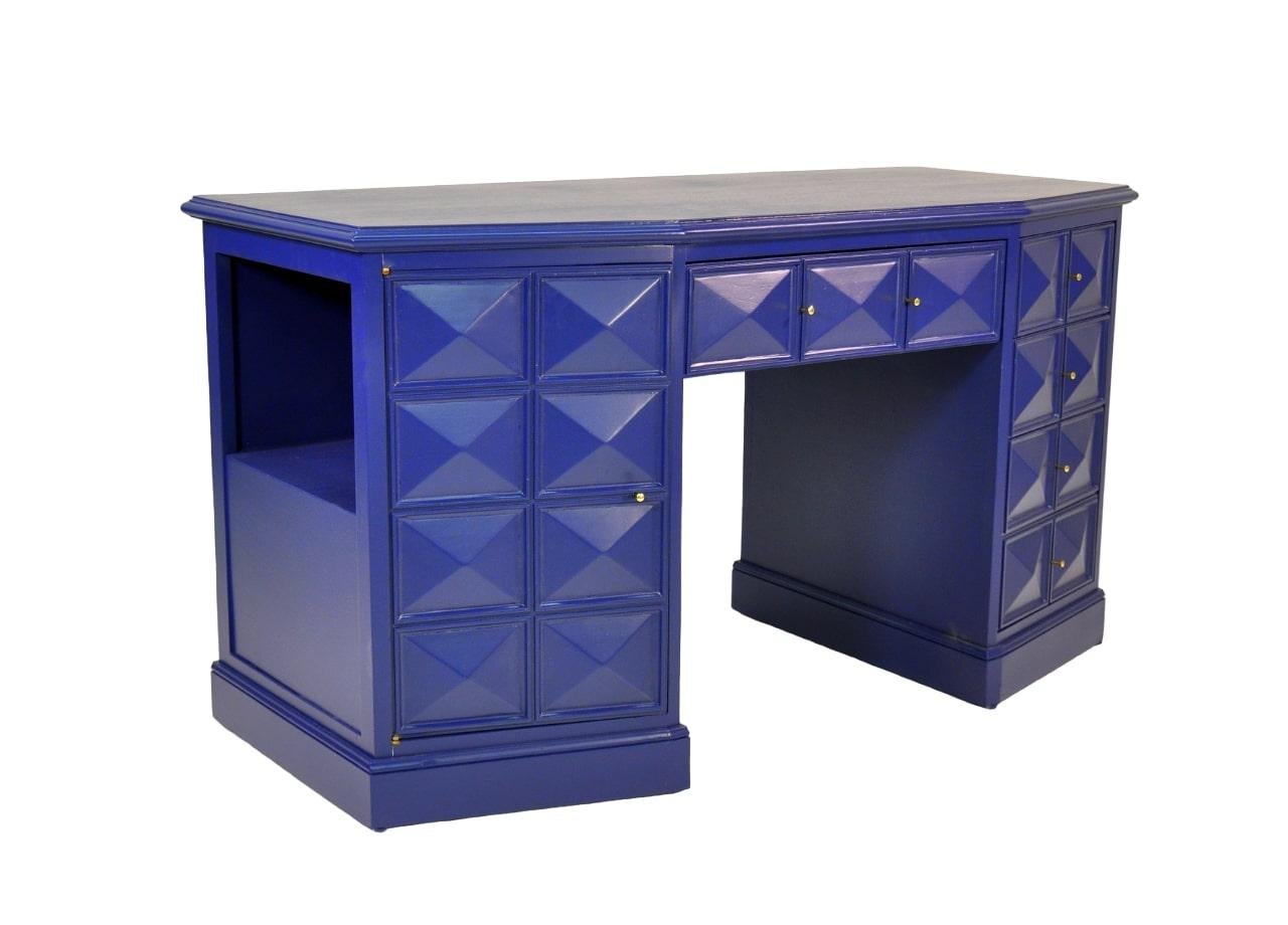 A gorgeous Hollywood Regency blue lacquered diamond front desk or vanity table with minimalist brass hardware. The writing desk features four drawers in a column on the right that all open and close effortlessly, a larger central drawer, and a