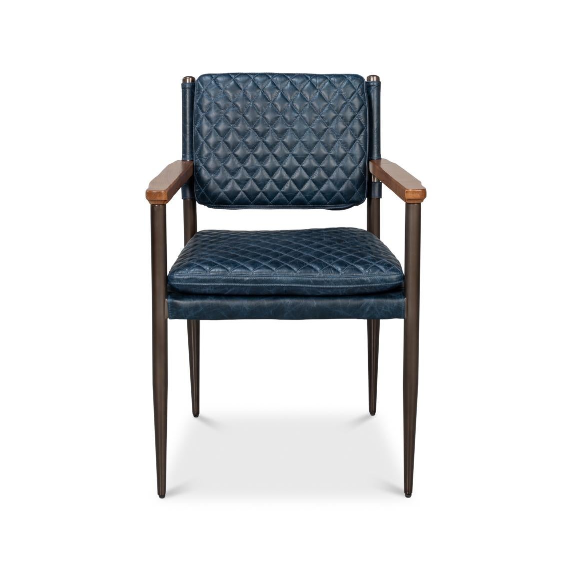 Le revêtement matelassé en cuir bleu Château offre une texture sophistiquée, tandis que le cadre métallique fin et les accoudoirs en bois chaleureux soulignent la silhouette élégante de la chaise. 

Les pieds fuselés soulignent son influence