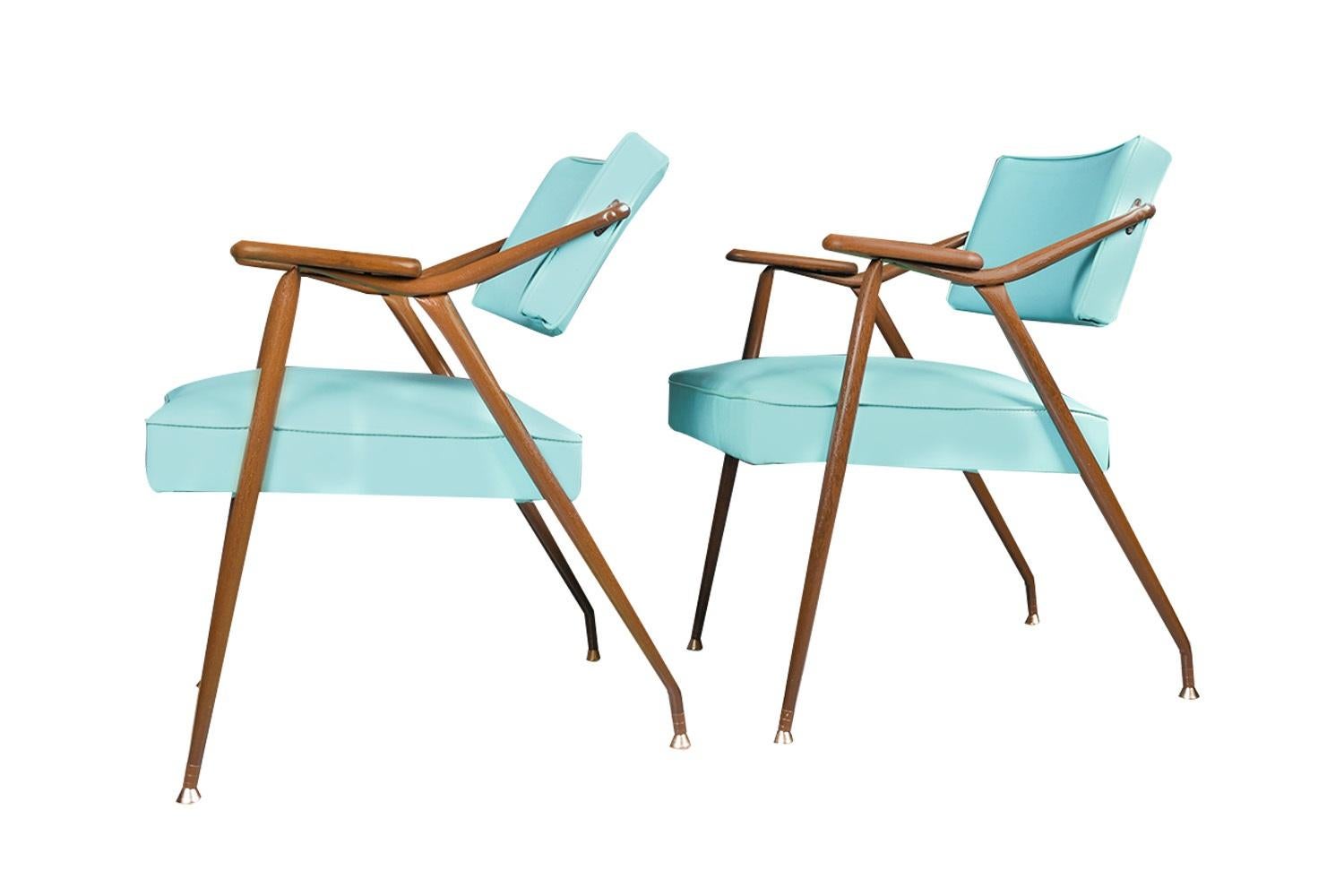 A gorgeous matching pair of lounge chairs by Viko Baumritter, USA, circa 1959. These Mid-Century armchairs have the lean of a lounge chair and the poise to draw attention. The dynamic sheen of the blue vinyl upholstery has an undeniable retro
