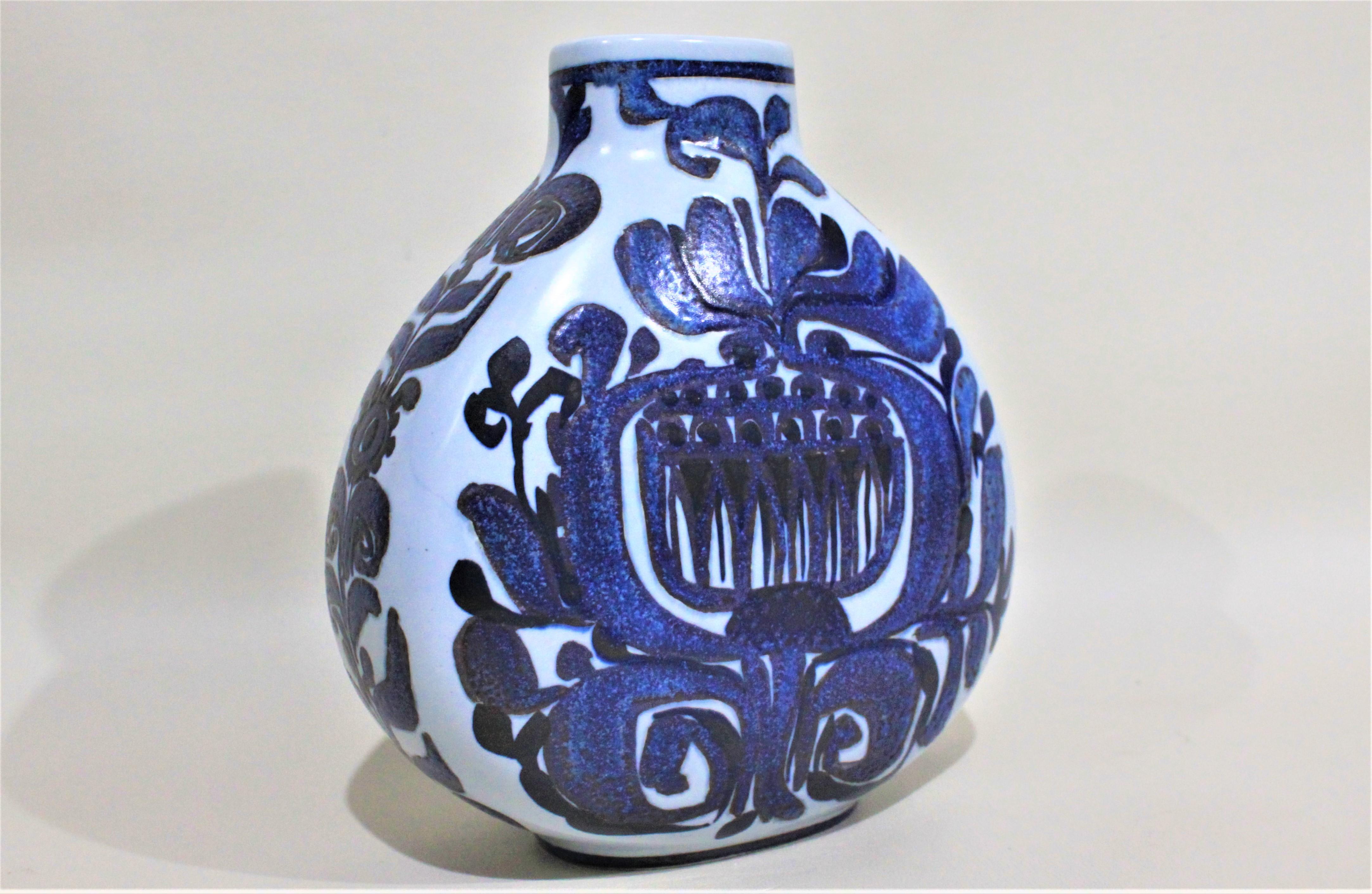 This Danish art pottery vase was made by Royal Copenhagen in the period and style of midcentury Modernism. The vase is done with a hand painted cobalt blue decoration over a light, or robin egg blue background. The vase is clearly signed with the