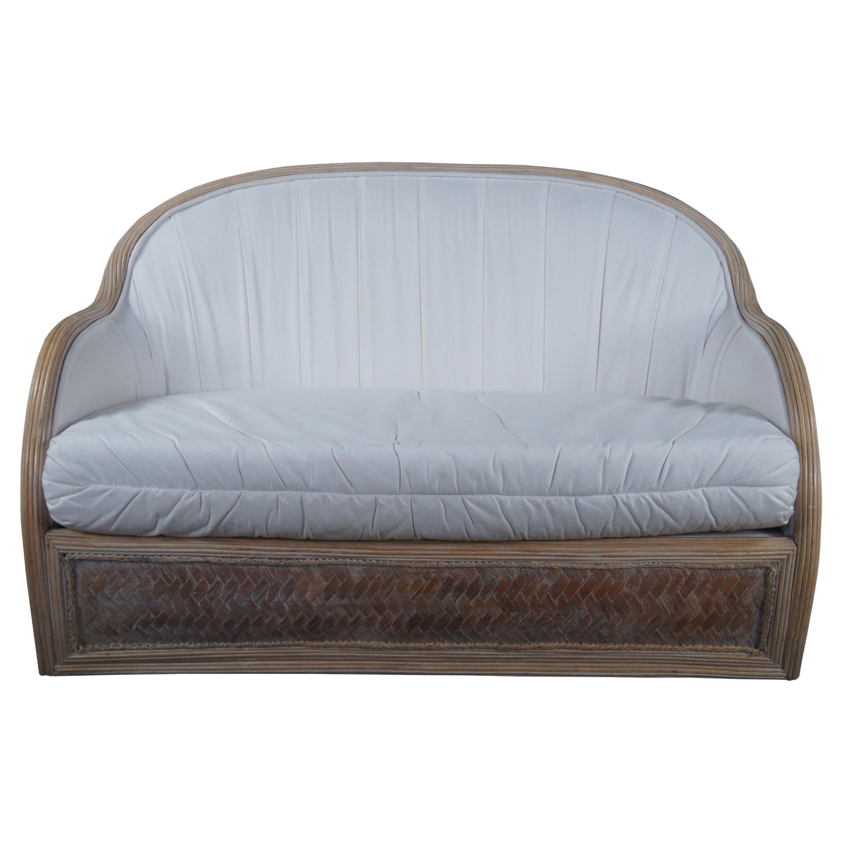 A quaint vintage Bohemian barrel back loveseat, circa 1970s. Made from a contoured split reed frame with woven rattan panels. Features a white upholstery with removable cushion. Perfect for a library, den or sunroom.