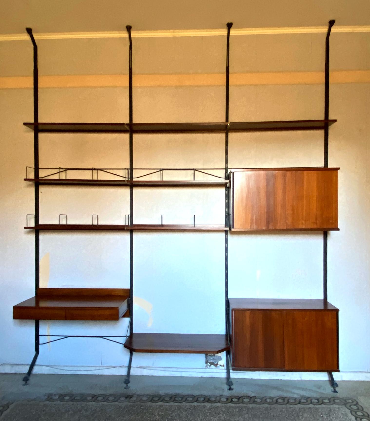 Designed by Ico Parisi 1958 for MiM, Rome. 
The bookcase consists of: Three sections, shelves, a desk with drawers, two closed cabinets, a larger shelf for a TV and several bookshelves with metal stands to keep the books standing straight. Metal tag