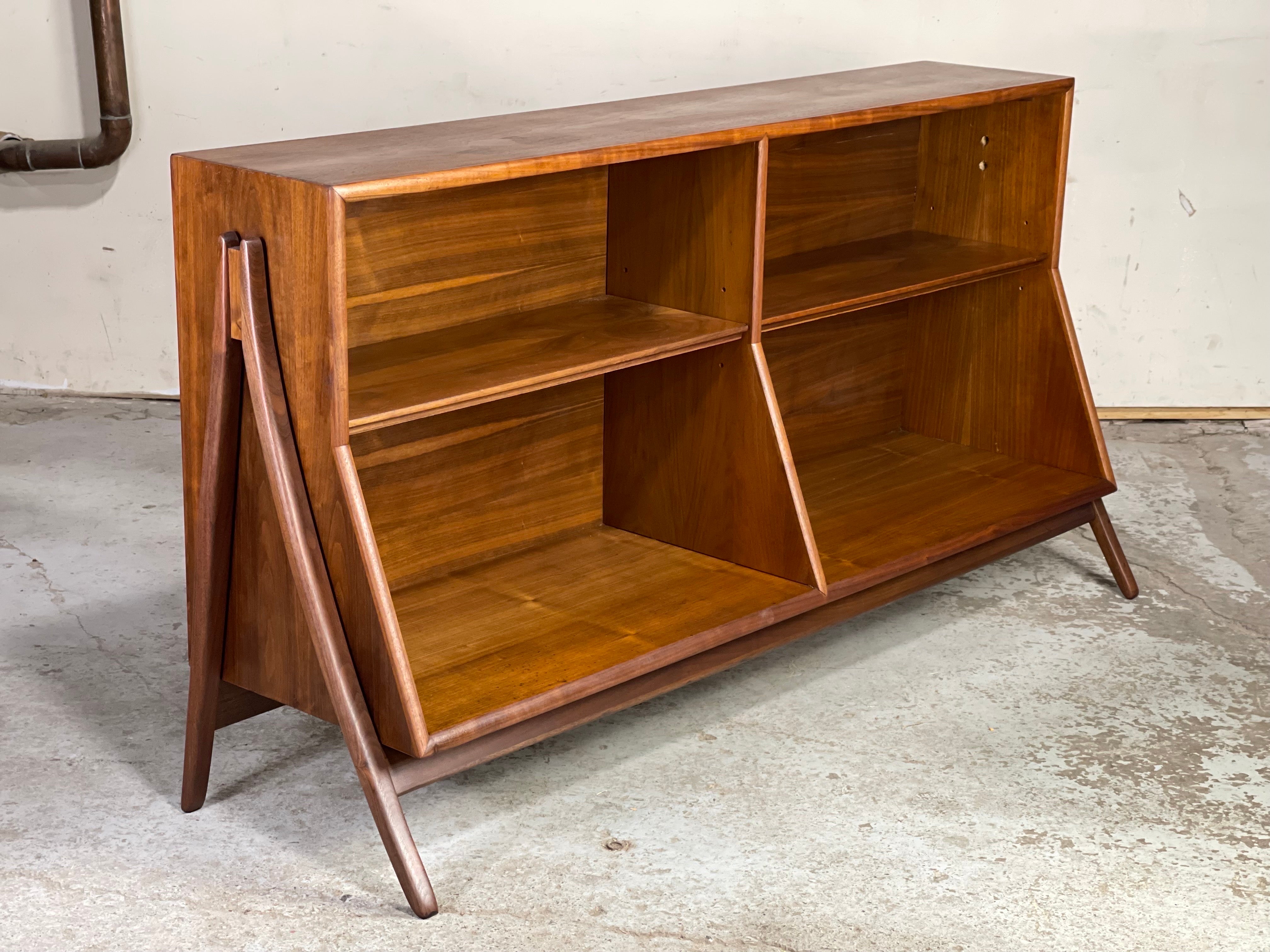 Mid century walnut bookcase by Kipp Stewart & Stewart MacDougall for Drexel; 1958. The classic mid century bookcase by Drexel Declaration featuring exoskeleton legs, adjustable shelves and sleek modernist lines. The walnut casing has been