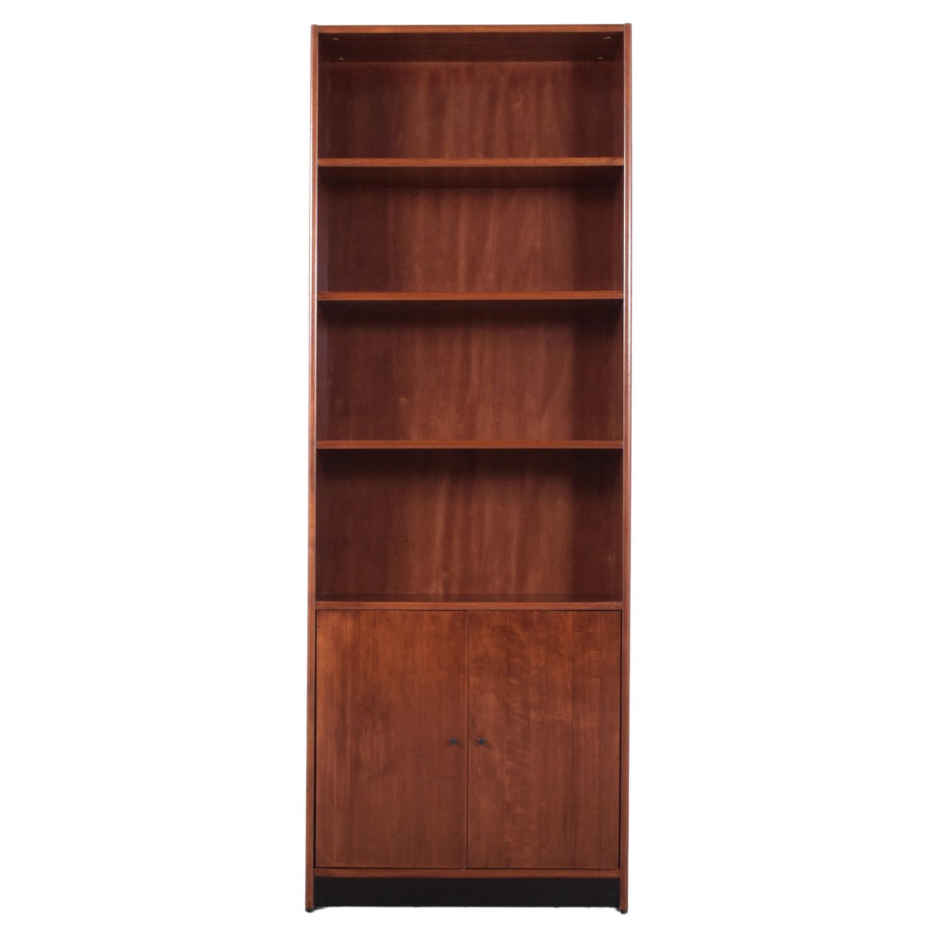 Indulge in the charm of vintage design with our expertly restored mid-century modern bookcase, skillfully crafted by our team of professional craftsmen. This eye-catching 1960s wall unit features three adjustable top shelves and two bottom doors,