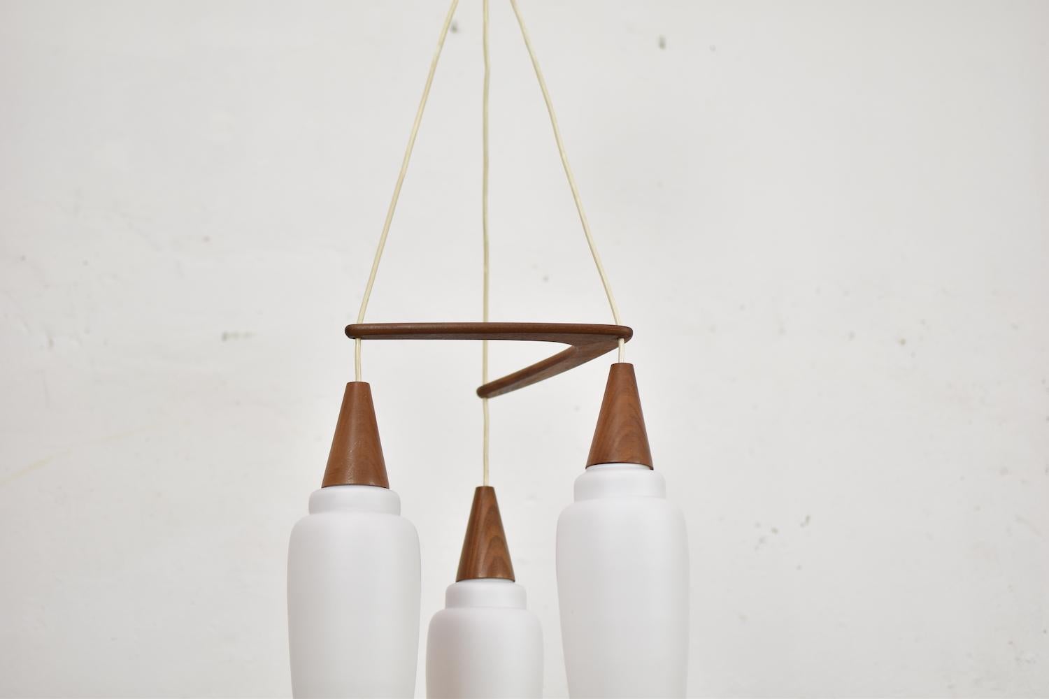 Mid-Century Modern pendant by Philips, The Netherlands, 1950s. This ‘Boomerang’ pendant is made out of teak and three opale glass shades. Very good original condition.