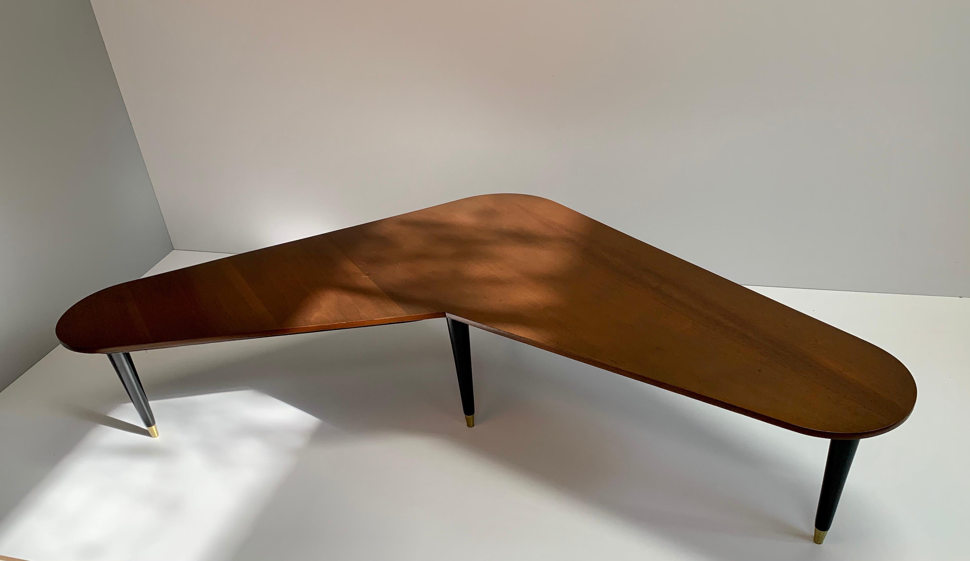 For your consideration, boomerang shaped table made in the 1960s, mahogany wood and brass leg bushings, professionally restored.