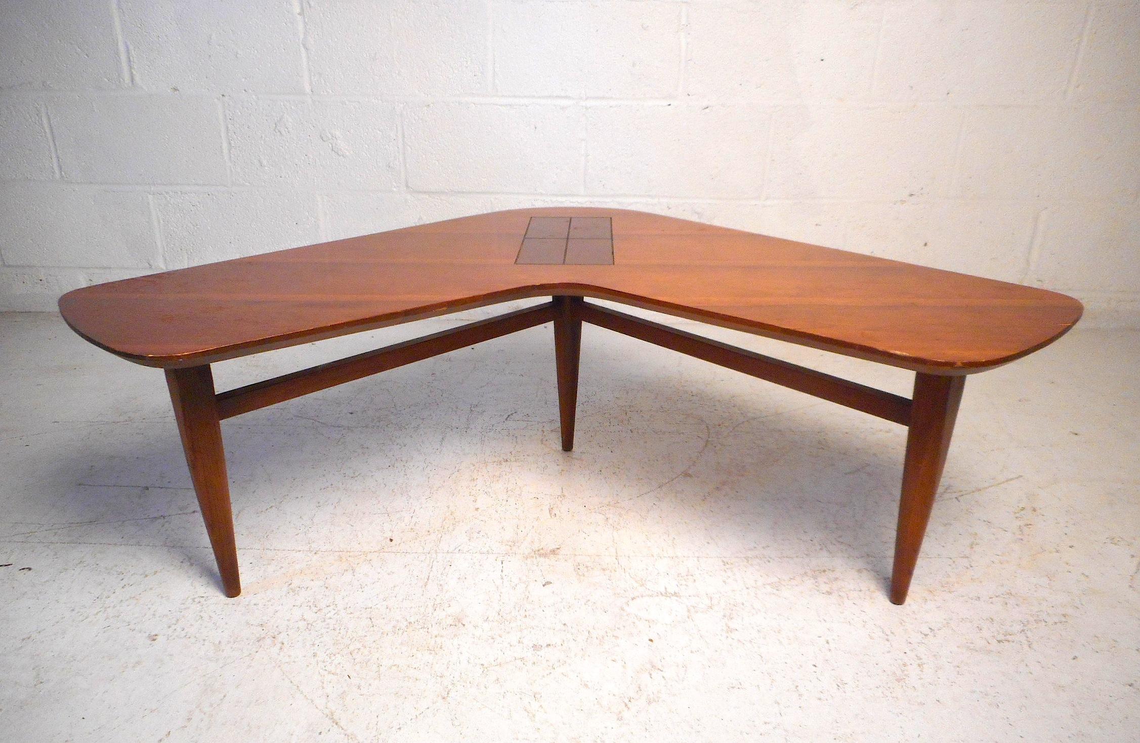This unusual midcentury boomerang table features a sturdy finished walnut construction, sleek tapered legs connected by stretchers, and a beautiful cross-sectioned burl inlay in the center of the tabletop. A rare midcentury design sure to make a