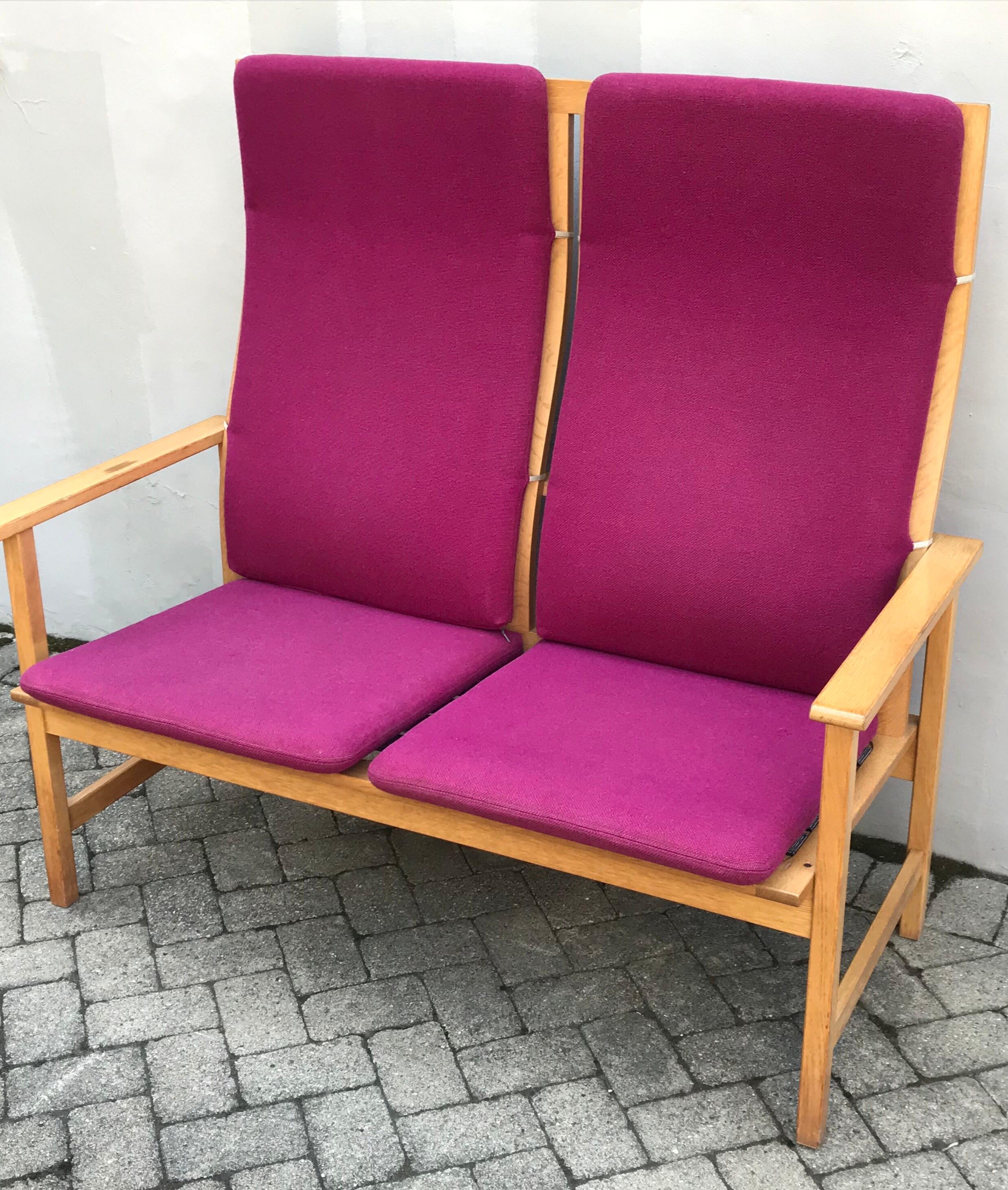 Mid Century bentwood oak frame two-seat bench by Borge Mogensen for Fredericia Stolefabrik, Denmark. Maintains original vibrant raspberry colored cushions, wear appropriate, missing one strap down, one cigarette burn, no stains, many more years of