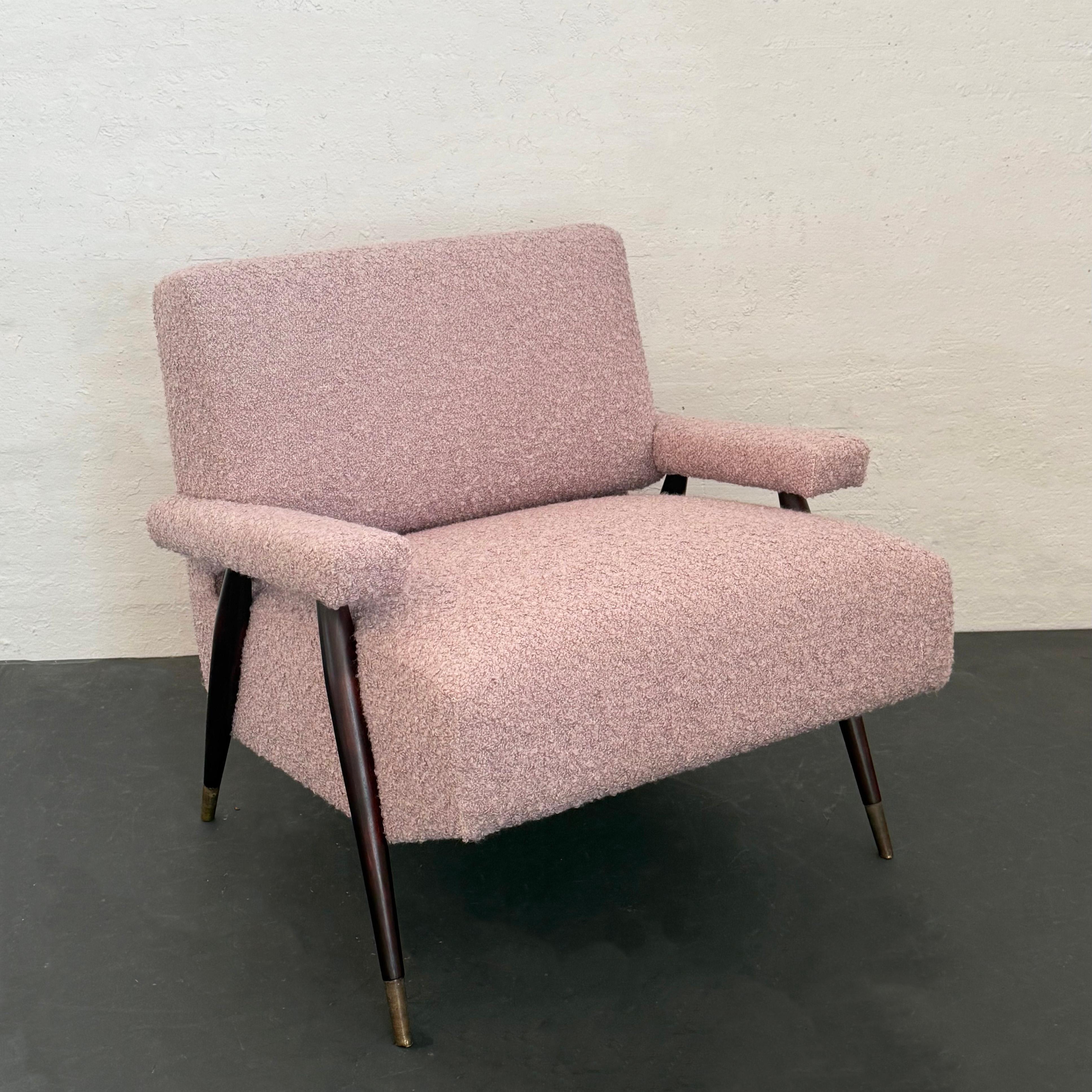 Questa poltrona da salotto in stile Mid-Century Modern è caratterizzata da una silhouette classica con un profilo a scodella completamente imbottito con seduta, schienale e braccioli rivestiti in cotone bouclé rosa pallido. La sedia è sostenuta da
