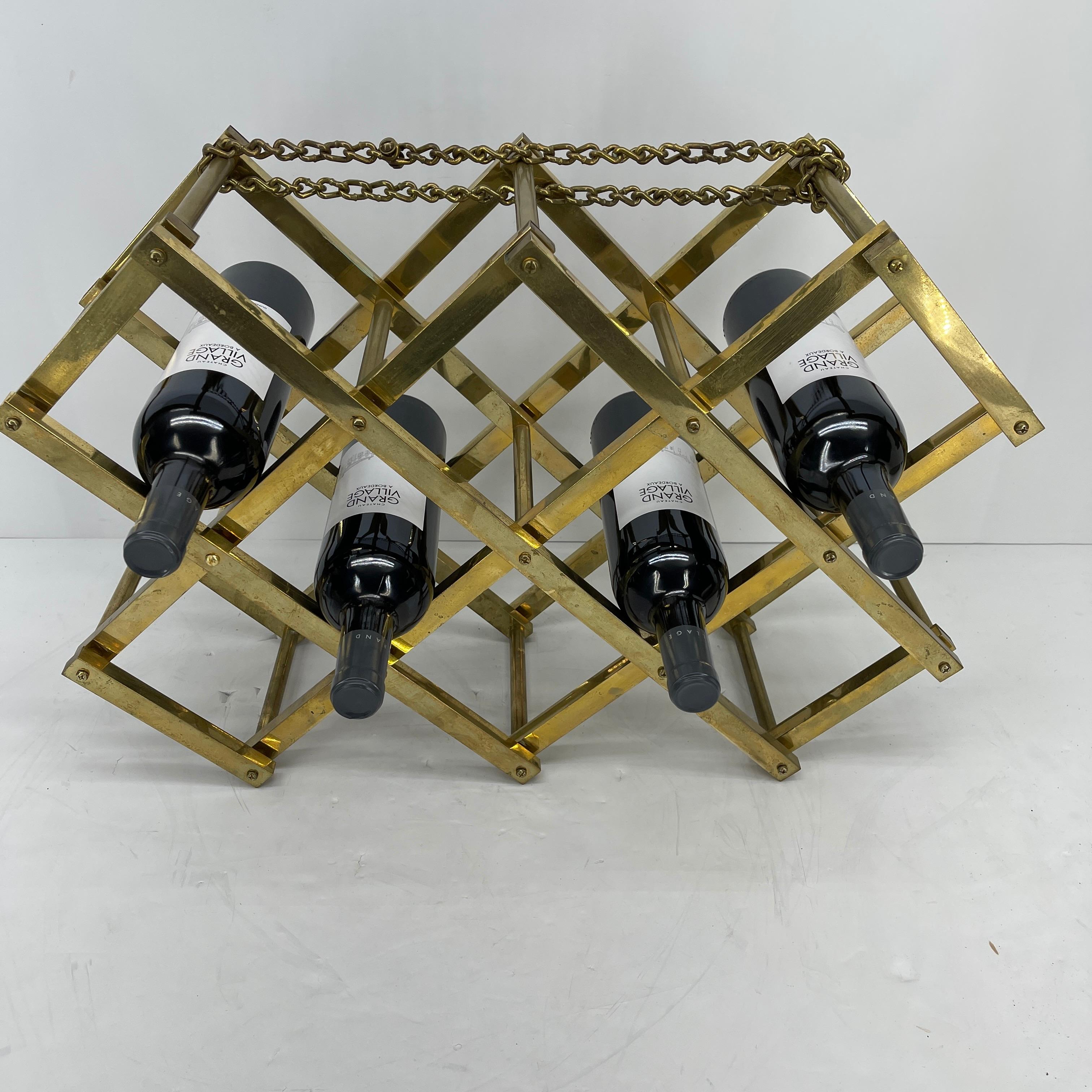 Mid-Century Modern brass wine rack. This vintage elegant wine bottle holder is sturdy with it's bold brass chain holding all the bottles in place. The folding rack holds 10 ten bottles of wine. The brass has a vintage patina, which adds to it's