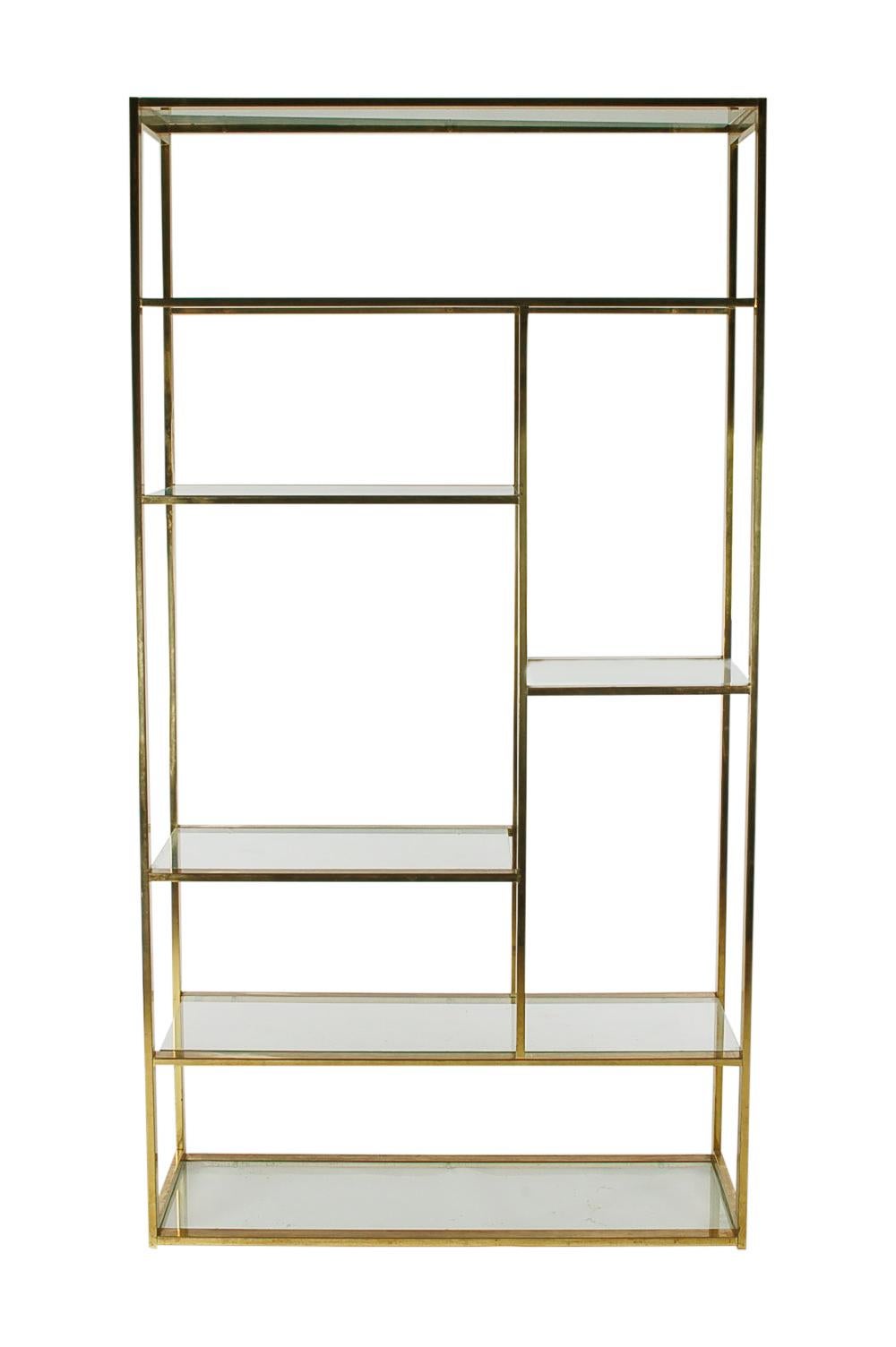 A beautiful modern asymmetrical étagère attributed to Milo Baughman. It features a brass rectangular frame with assorted clear glass shelving.