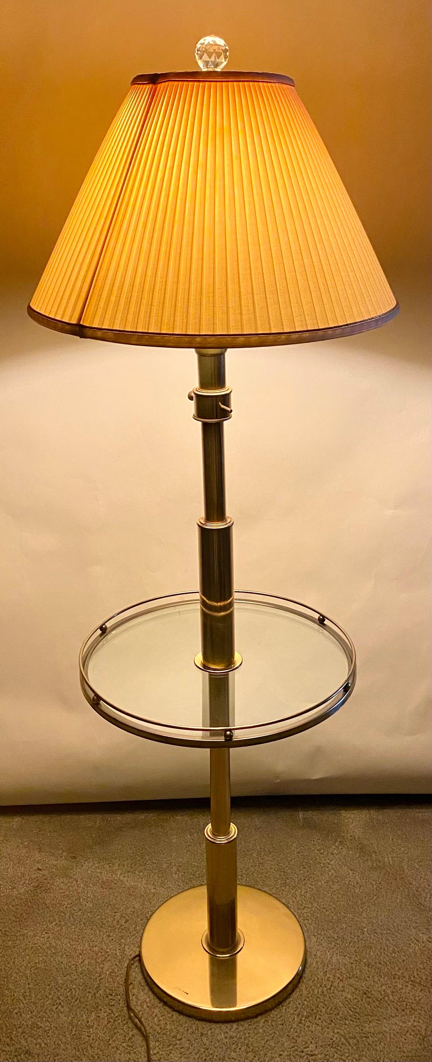 Une lampe de table classique et élégante de style moderne du milieu du siècle. La lampe de table est finement fabriquée en laiton. La table est dotée d'une base ronde en laiton et d'un plateau en verre. Elle est joliment encadrée de laiton dans un