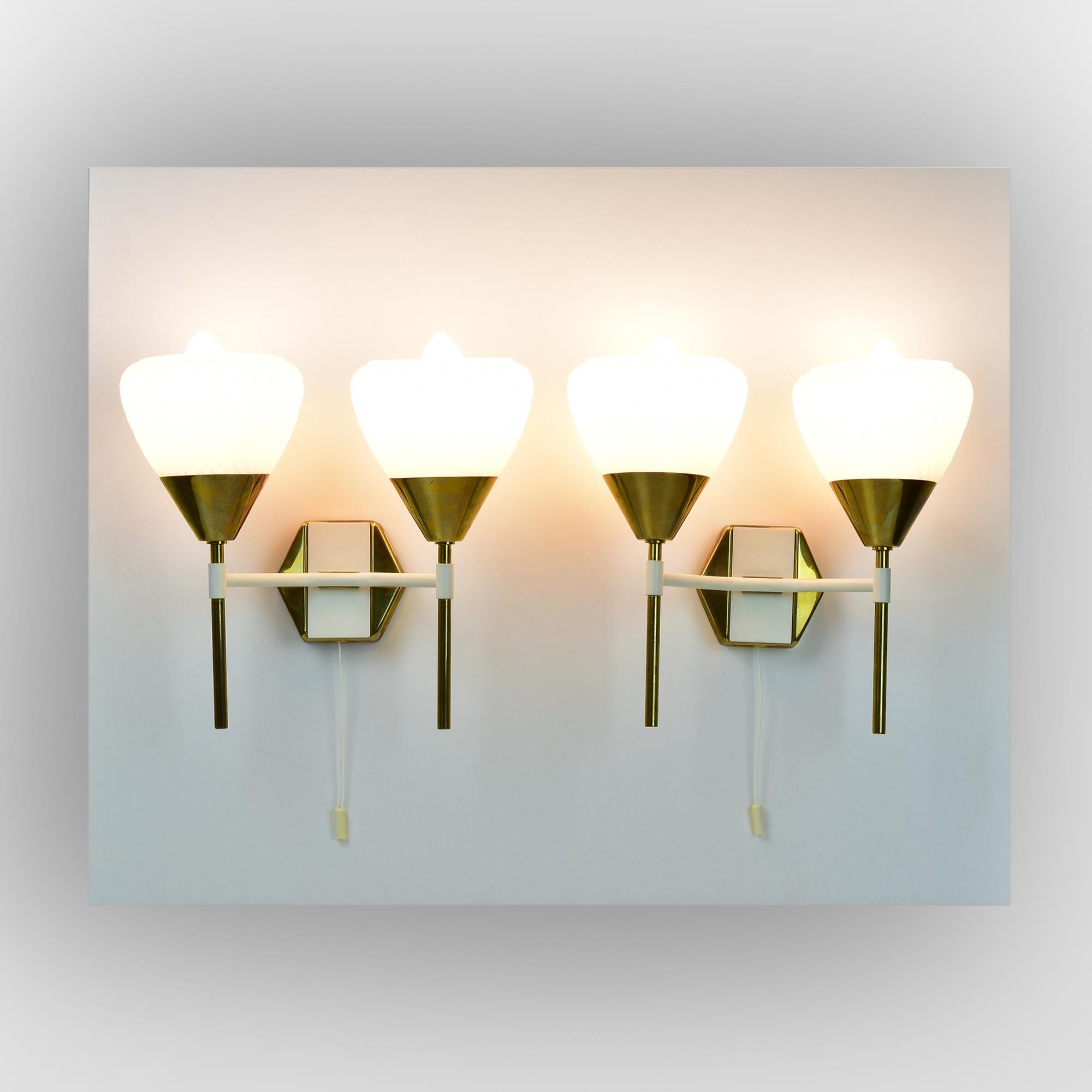 This elegant pair of mid-century modern wall sconces features a striking combination of brass and textured white glass. The diamond-patterned glass shades emit a soft, diffused light, perfectly complementing the sleek brass accents. These sconces