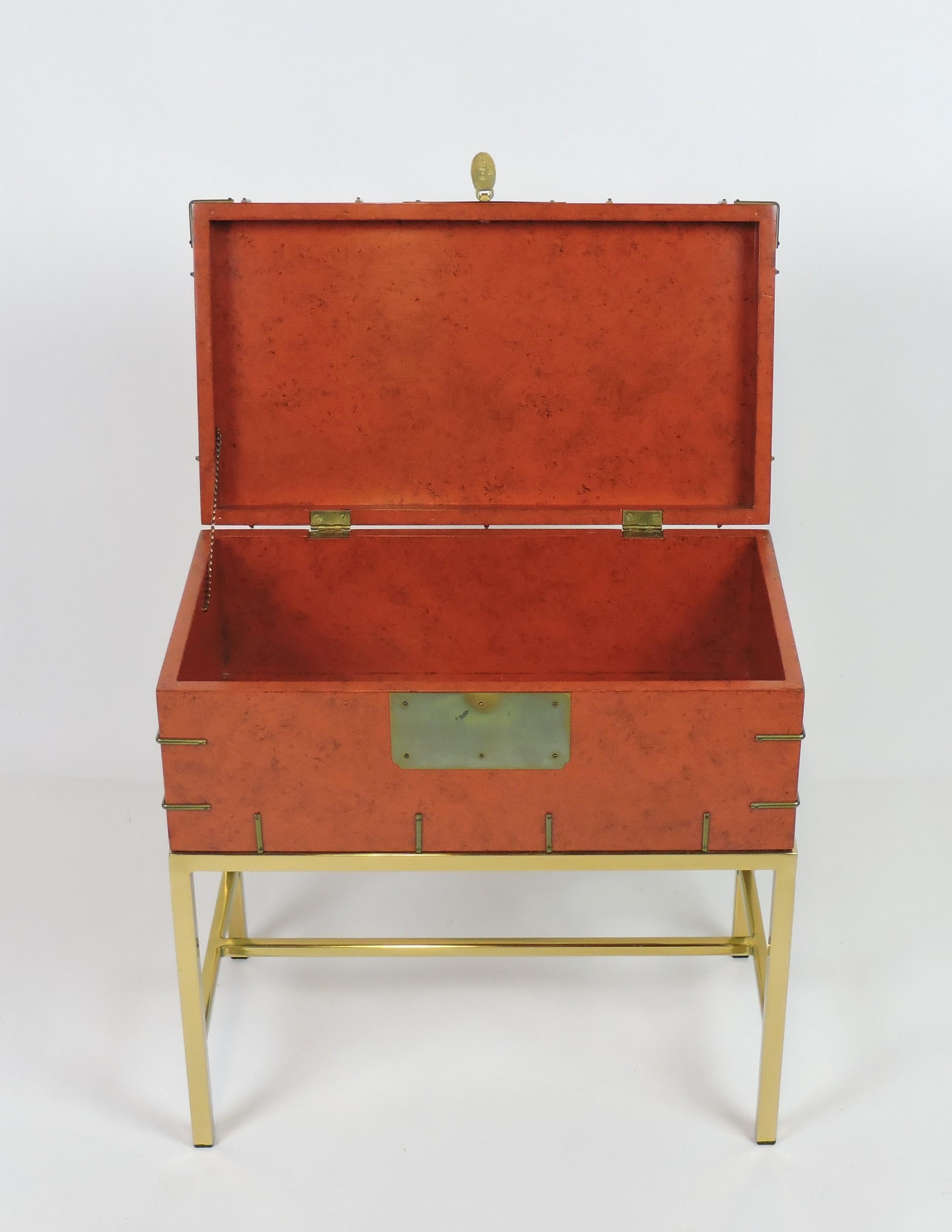 Lovely vintage campaign style chest that could also be used as a small side table. This piece has a red-orange painted lacquer finish along with brass accents and it sits on a brass stand. Nice look and very good quality. 