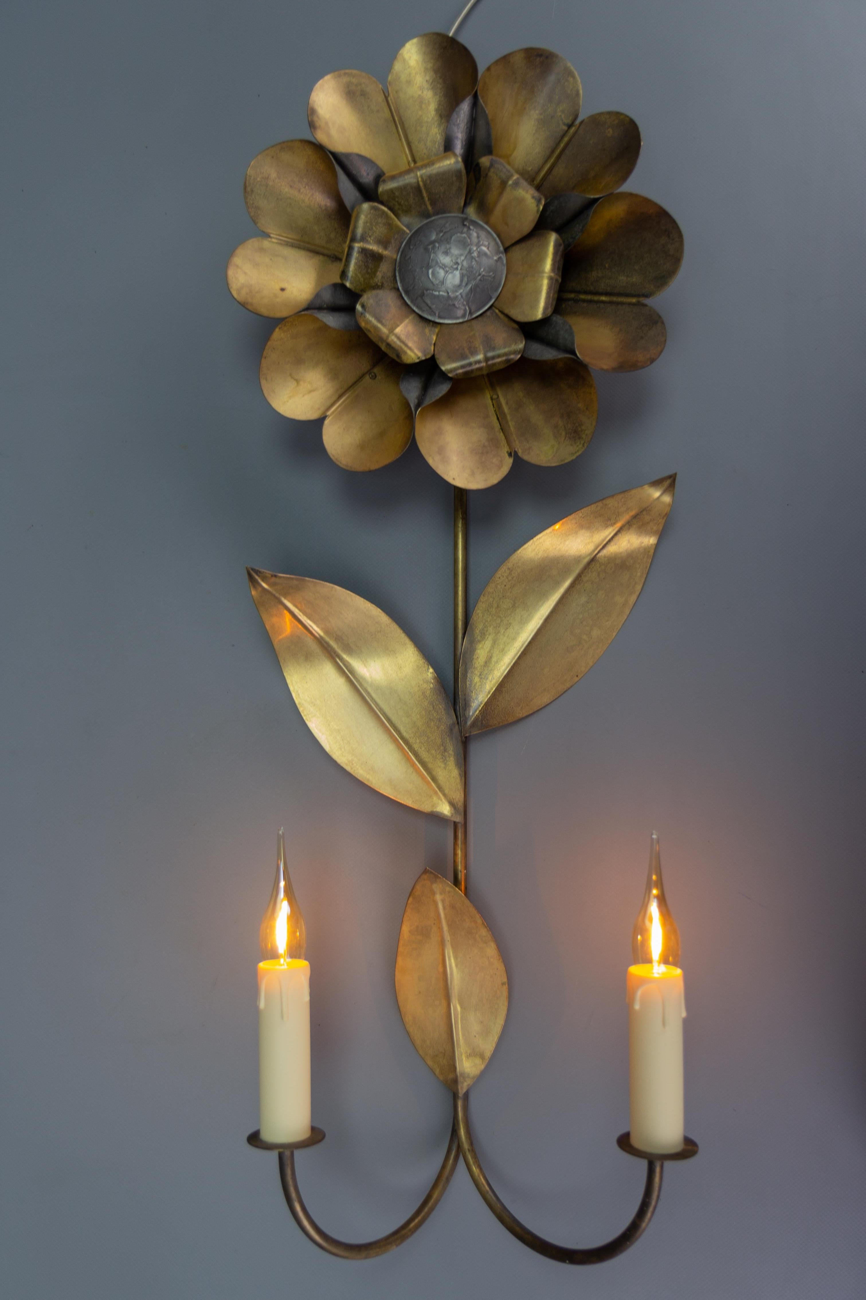 Mid-Century Modern brass and metal flower-shaped twin arm sconce, France, 1950s.
This beautiful Mid-Century Modern wall lamp features a flower- or daisy-shaped brass and metal body with twin arms, each with a socket for E14-size light