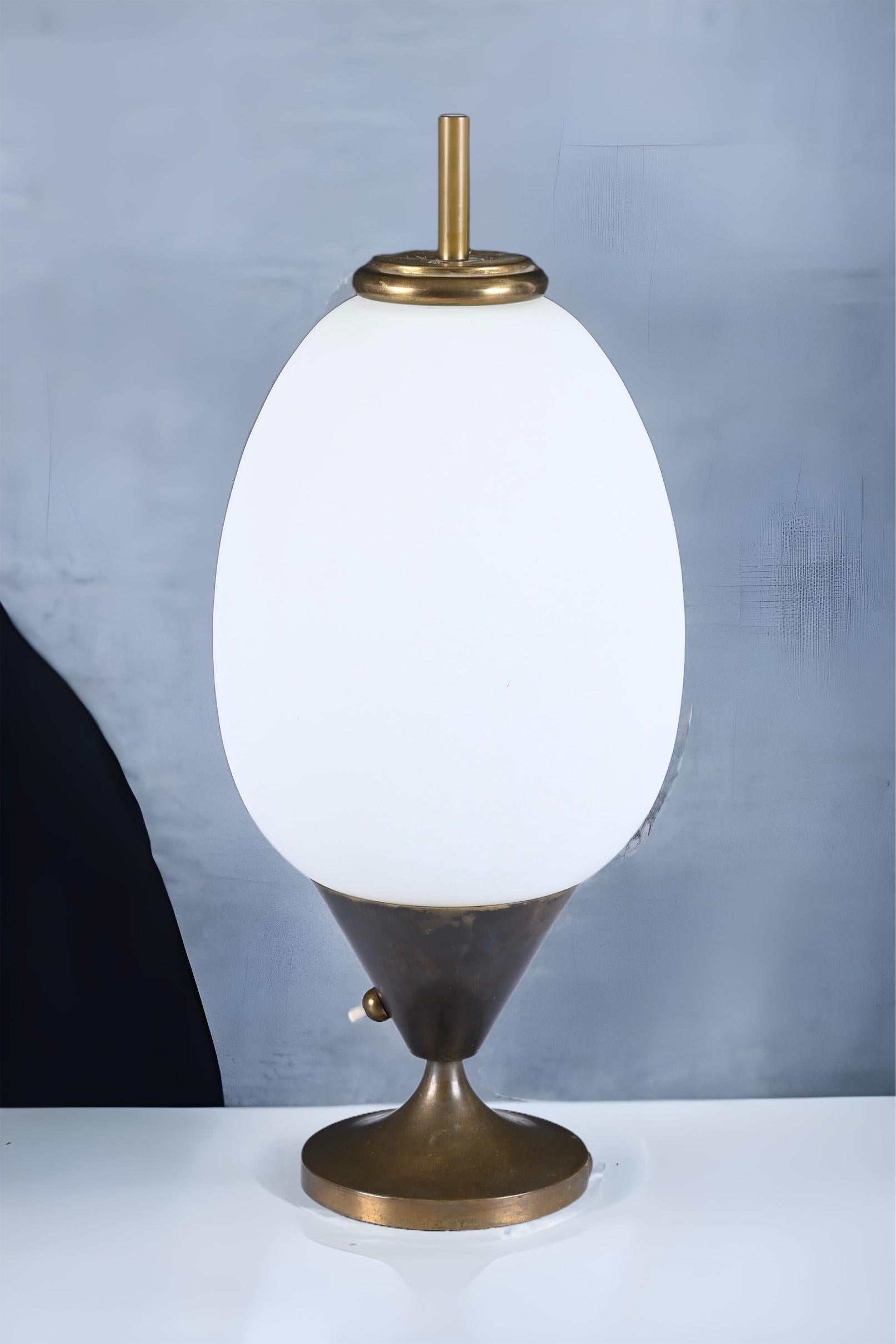 Superbe grande lampe de table ovoïde en laiton et verre opalin. Cette pièce unique a été conçue en Italie dans les années 1950.

La lampe est tout simplement étonnante en raison de ses lignes iconiques et délicates et de sa magnifique patine