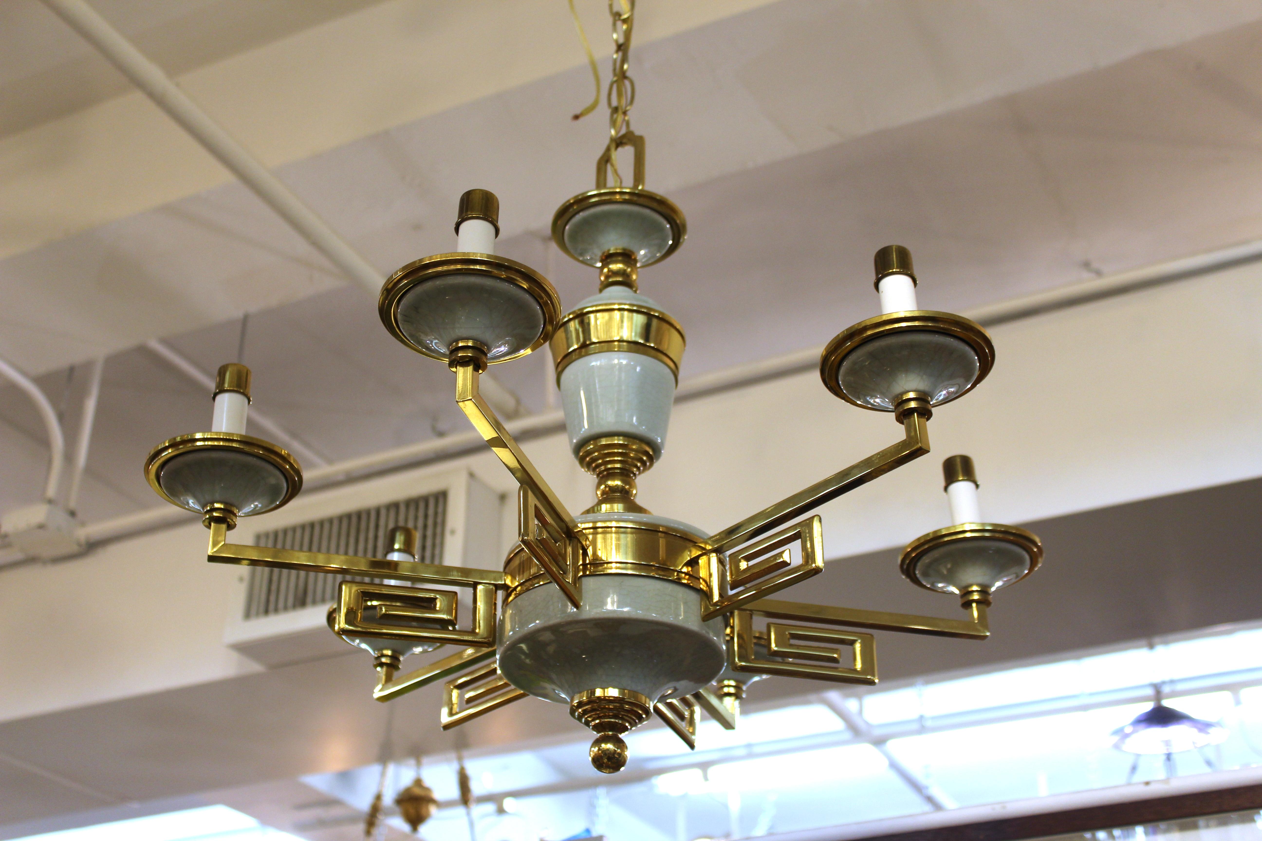 Mid-Century Modern chandelier in brass structure with inserted porcelain elements, in the manner of Tommi Parzinger. The piece has six arms supported by Greek key motif elements and is in great vintage condition.