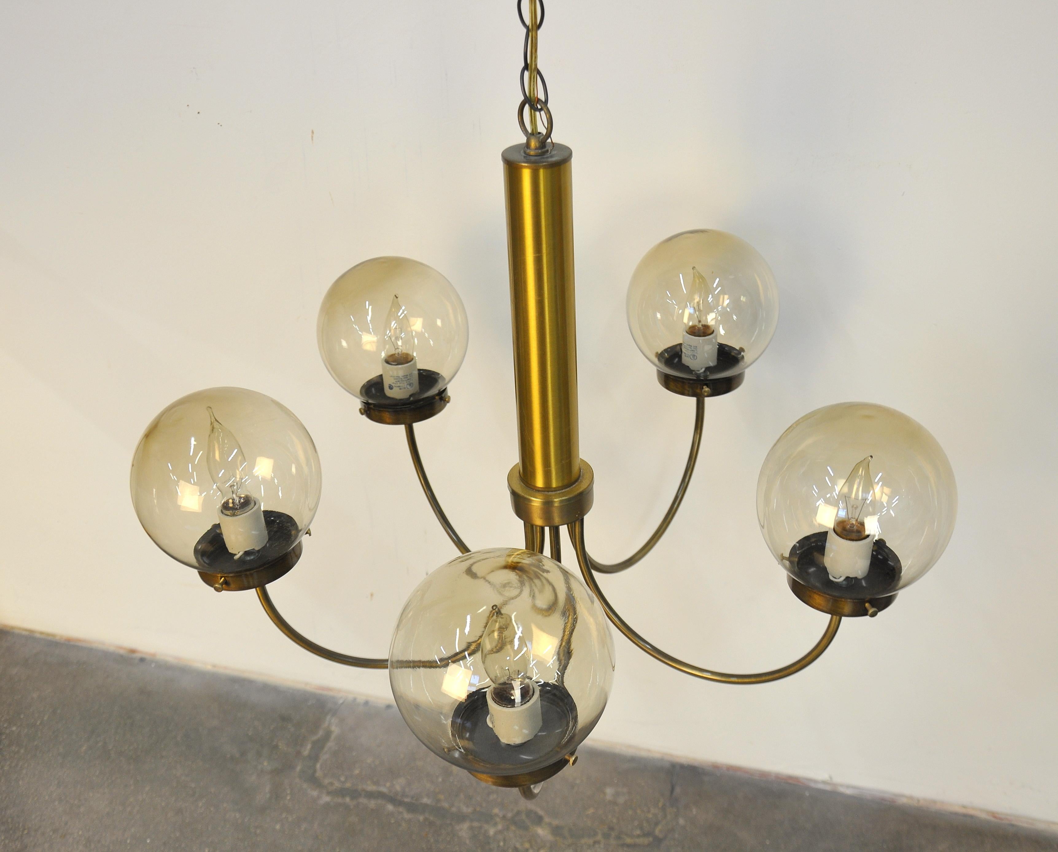 Vintage midcentury single tier pendant lamp featuring a tubular brass stem and five brass arms fitted with smoked glass globe shades. Works well with virtually any decor, from Scandinavian or Danish modern to Hollywood Regency, contemporary or