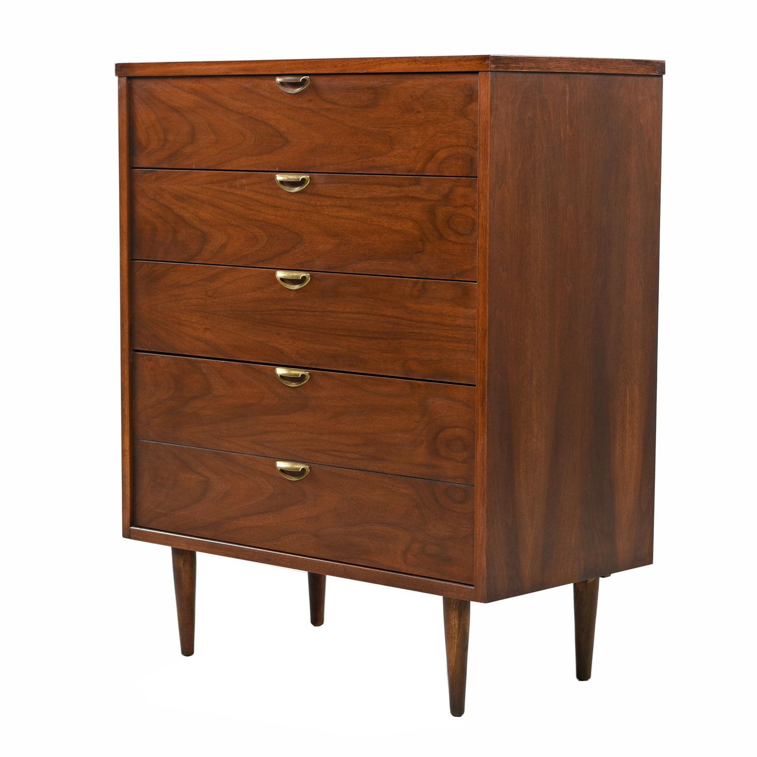 Mid-Century Modern American made highboy dresser or chest of drawers with brass accents. Made by Bassett, circa 1960s. This handsome chest features sculpted, scalloped shaped brass pulls on the drawers that perfectly contrast and compliment the
