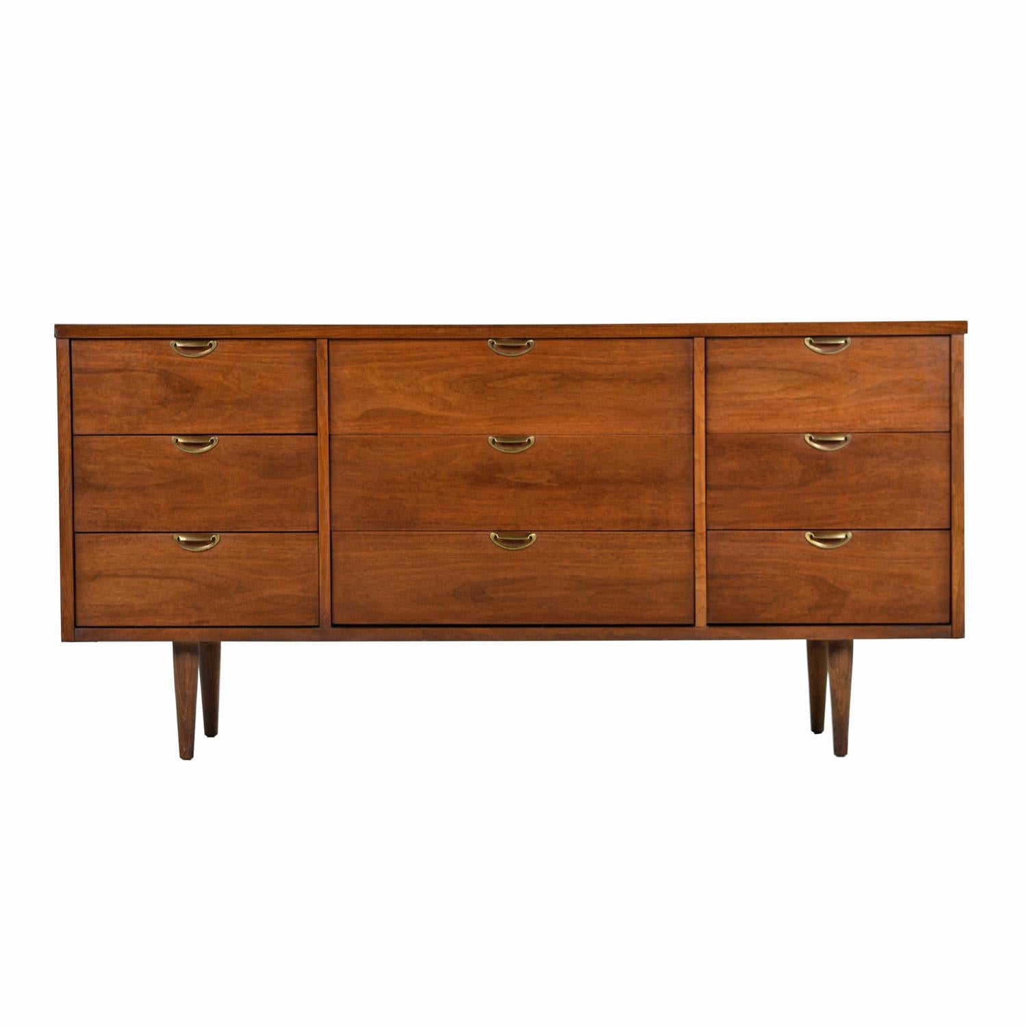 Mid-Century Modern American made 9-drawer dresser or credenza with brass accents. Made by Bassett, circa 1960s. This stunning triple dresser features sculpted, scalloped shaped brass pulls on the drawers that perfectly contrast and compliment the