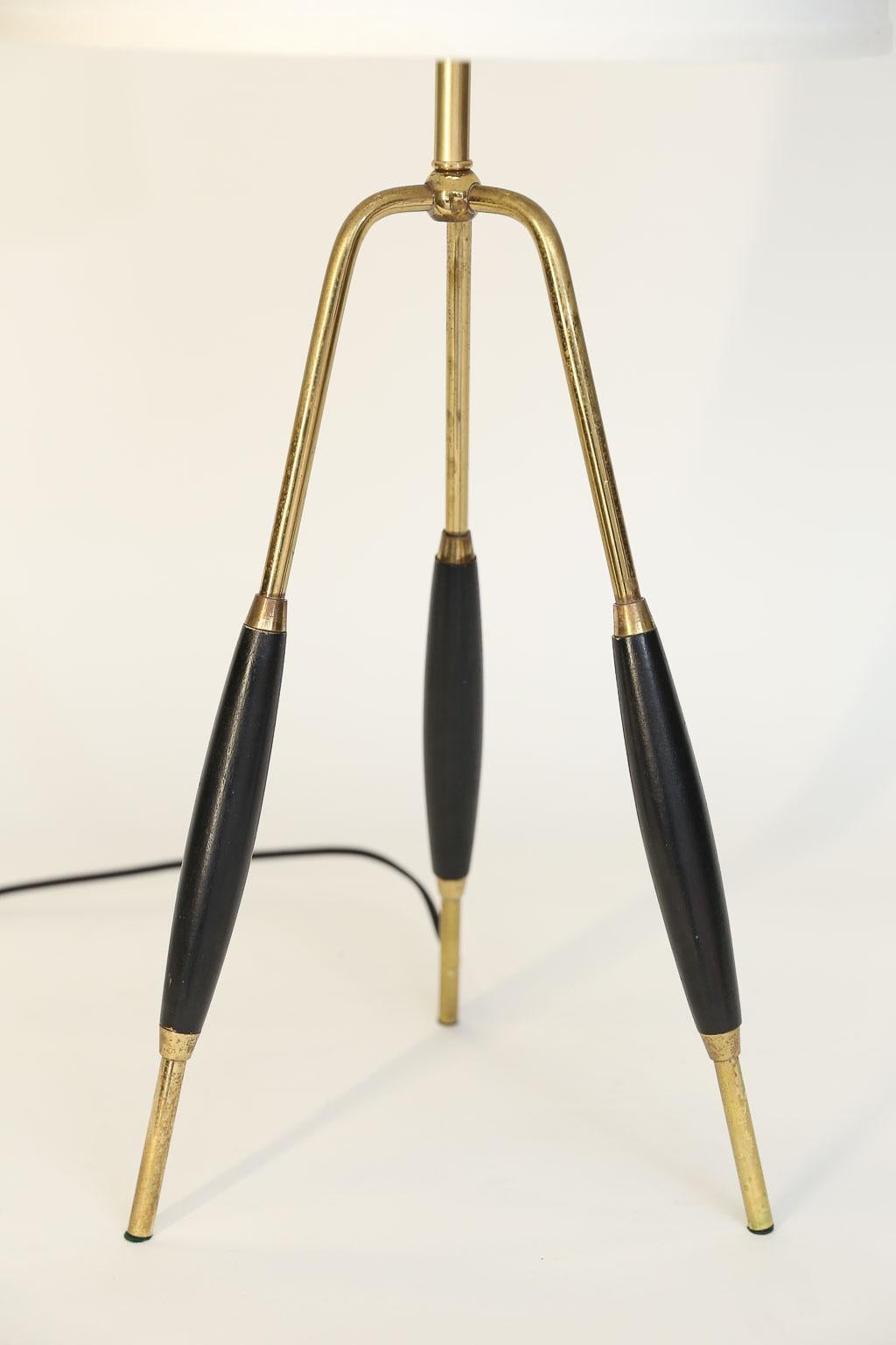 This midcentury tripod table lamp will surely add an updated modern look to any room. The newly wired lamp features a brass and wood tripod base, a new shade and a black cloth cord.