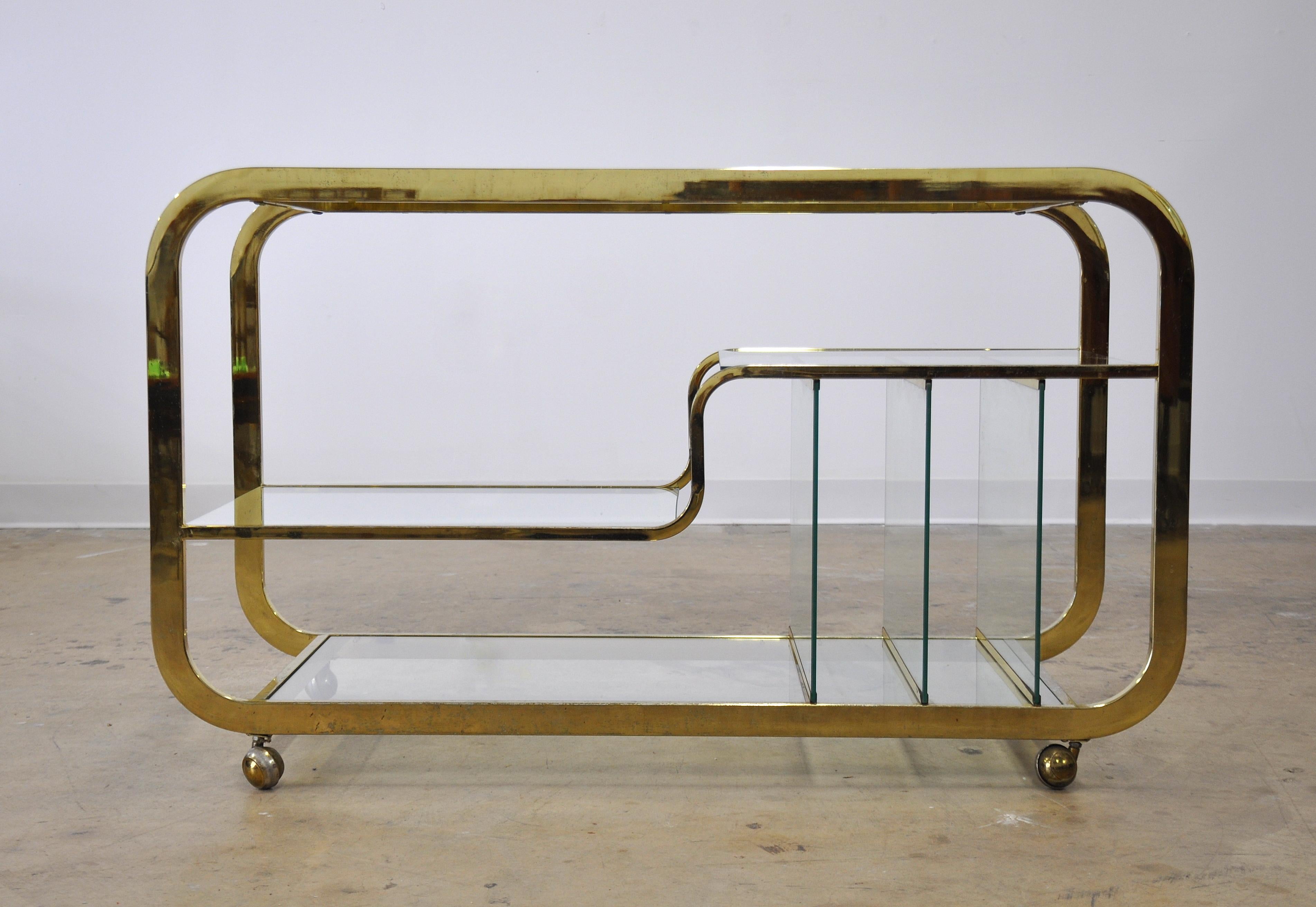 A fabulous vintage three-tier rolling bar cart, serving trolley and/or media console. The table features a brass frame and three tiers with inset clear glass and dividers that can accommodate a turntable, records and books, as well as bottles, bar
