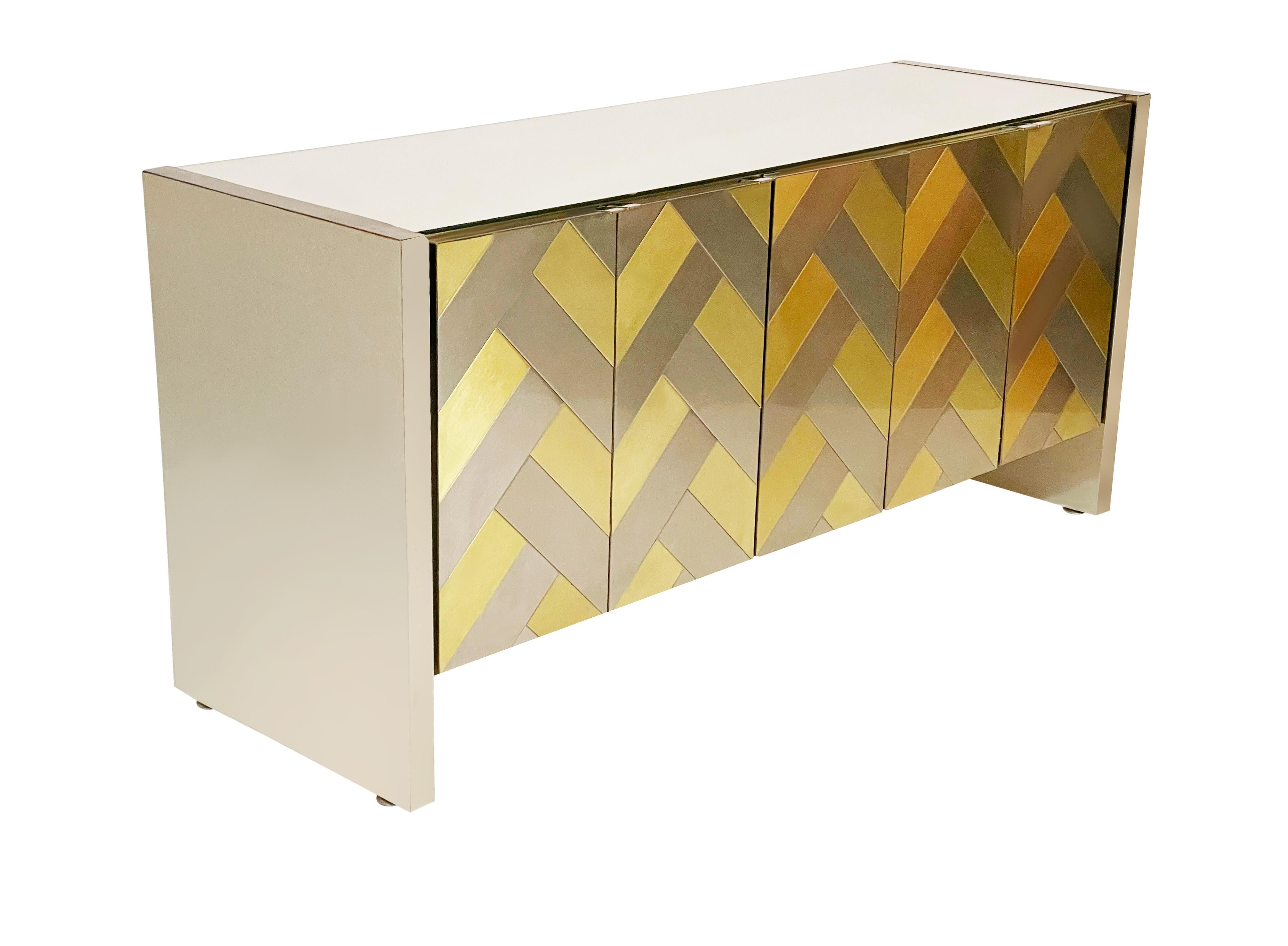 A stunning five door cabinet made by Ello circa 1970's. This hard to find model features brushed brass and brushed steel fronts in a herringbone / chevron design. The top is mirror and the sides are brushed steel. The interior has two adjustable