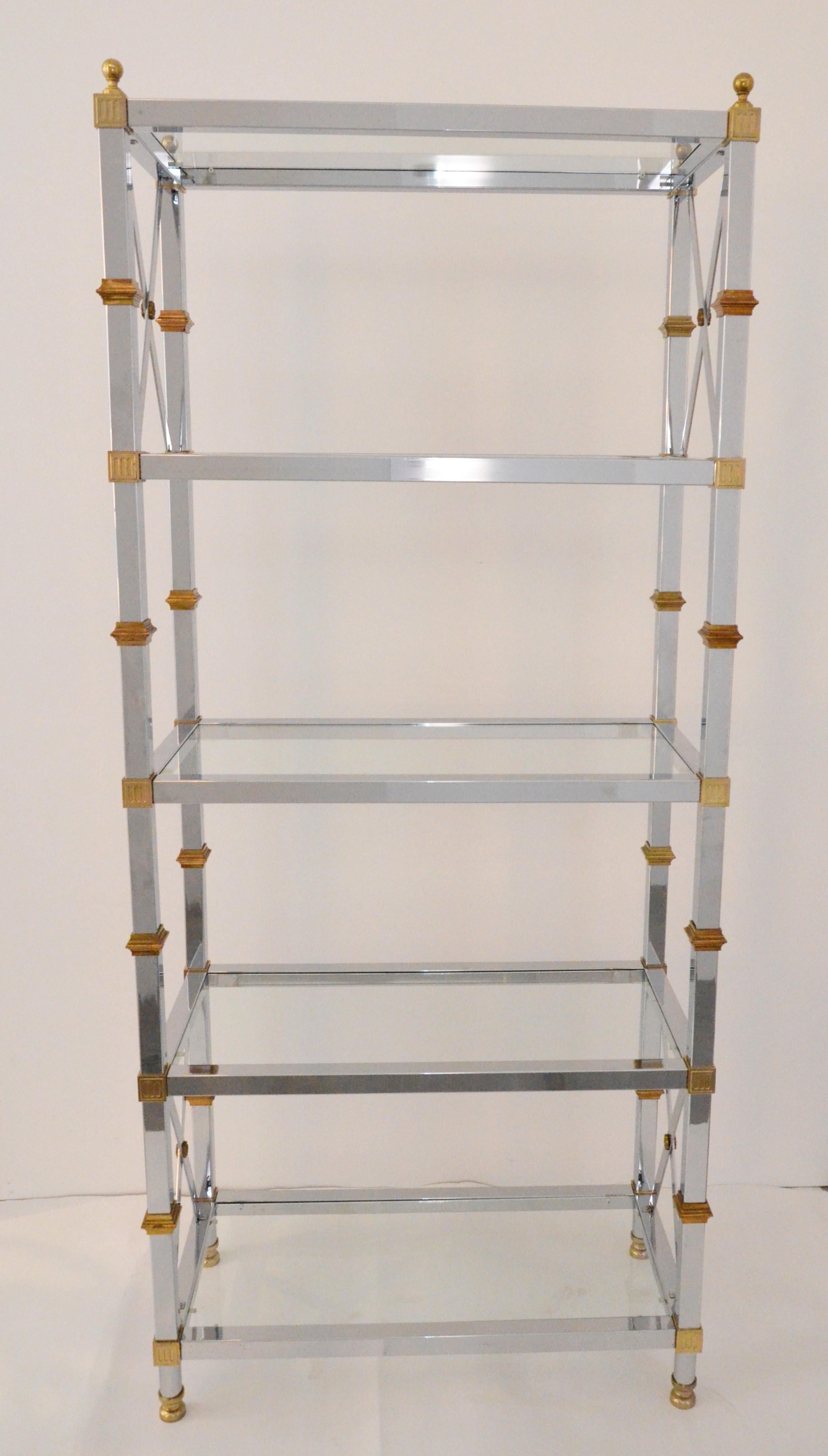 Offered is a Mid-Century Modern brass, chrome and five-glass shelf Regency style Hollywood Glam étagère. This shiny chrome and glass étagère has decorative brass accents and brass ball finials. This piece is incredibly versatile and could perform so