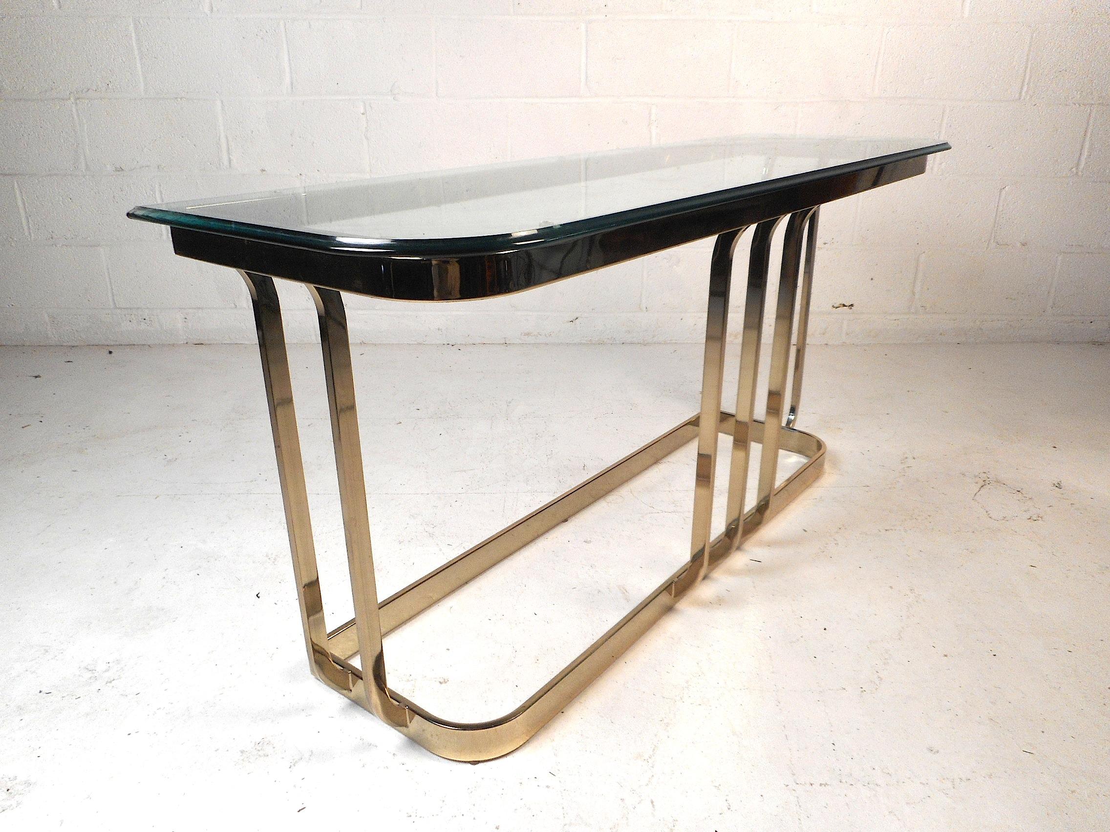 This impressive midcentury console table features a pane of half-inch thick beveled glass, and a brass-plated base with elegantly tapered supports. This table would make a great addition to any home, office, or business. Please confirm item location