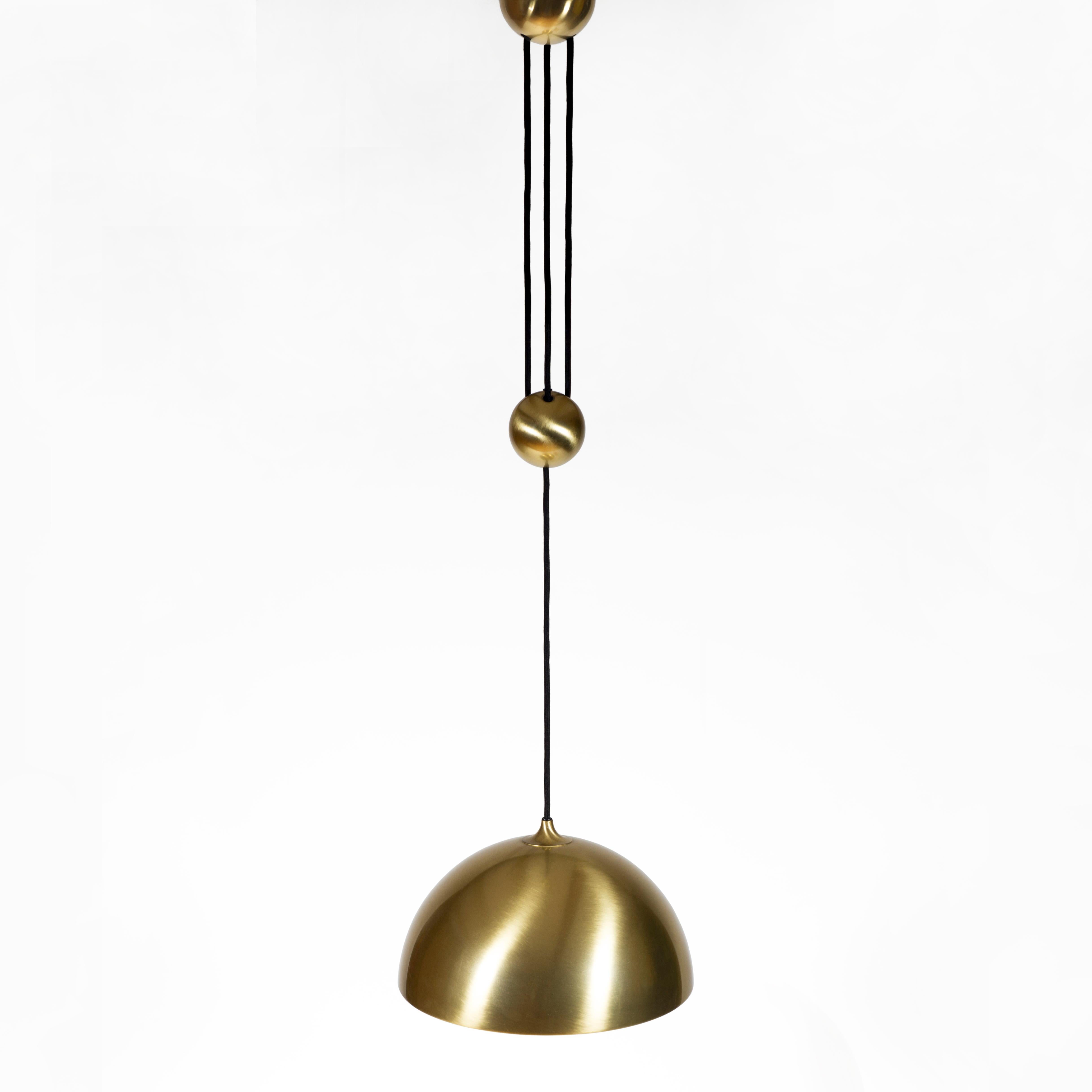 Elegante lampada a sospensione in ottone originale della metà del secolo scorso con contrappeso, progettata e realizzata da Florian Schulz in Germania prima del 1980.
Il lampadario regolabile in altezza con peso centrale è completamente in ottone e
