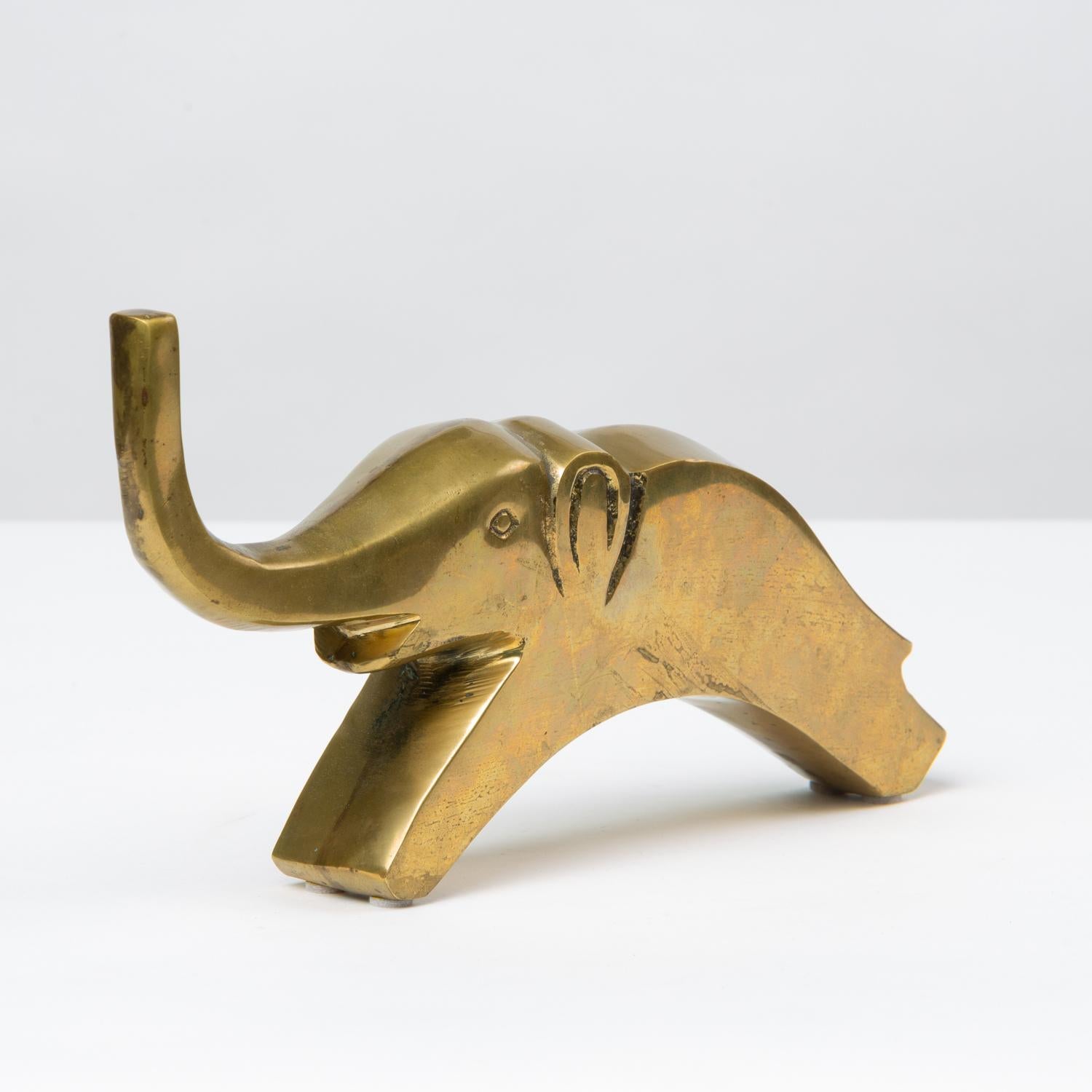 A charming brass paperweight or small sculpture in a modernist rendering of an elephant. The cast brass object has molded ears and eyes, and an upturned trunk. It sits solidly on the front and back “feet.” Unsigned. 

Condition: Excellent vintage