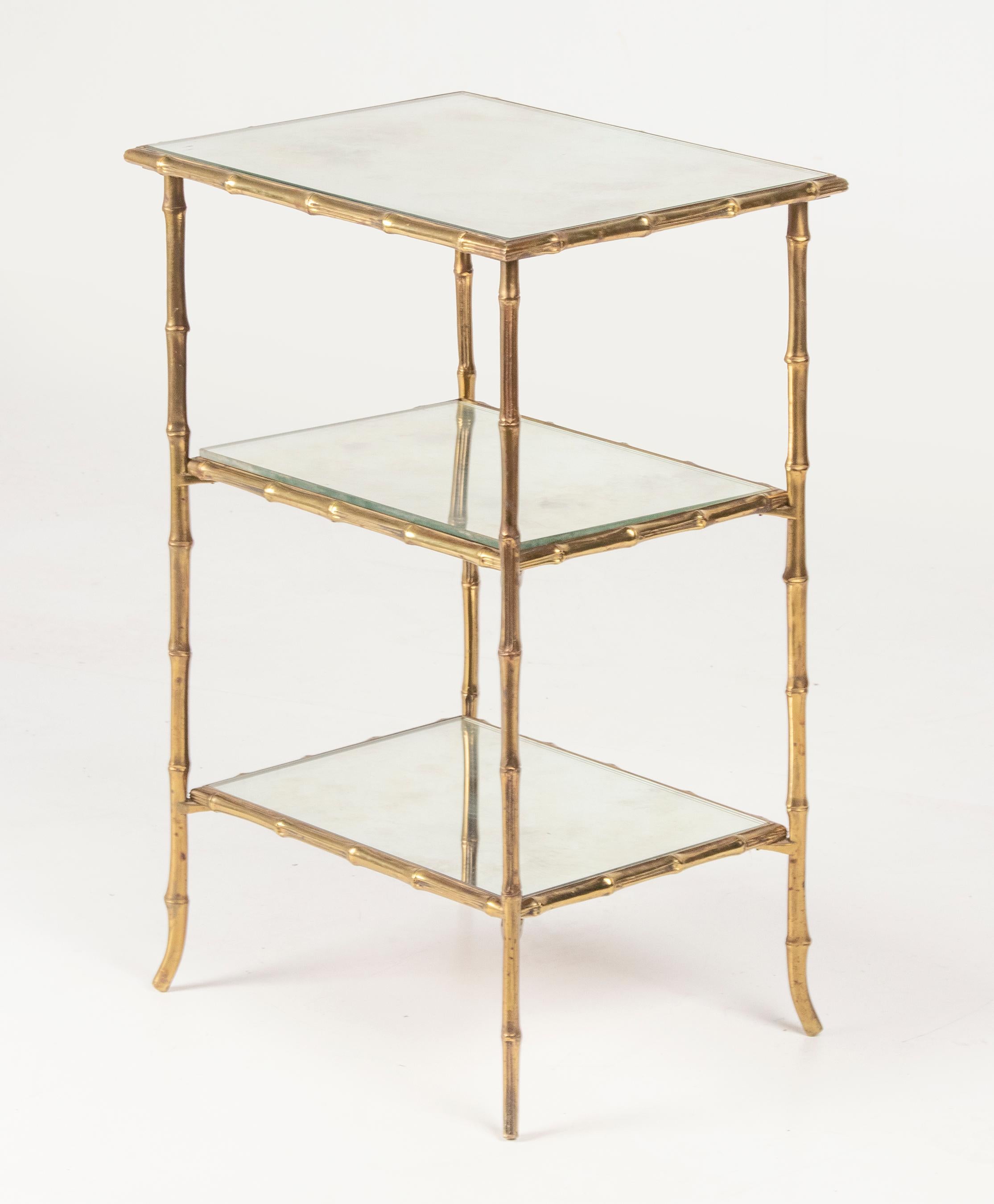 A stylish solid brass side table attributed to Maison Baguès. The frame is made of solid brass in faux bamboo with tapered legs at the endings. The brass have the original patina. The mirror glass tops have some wear, during aging, but this gives