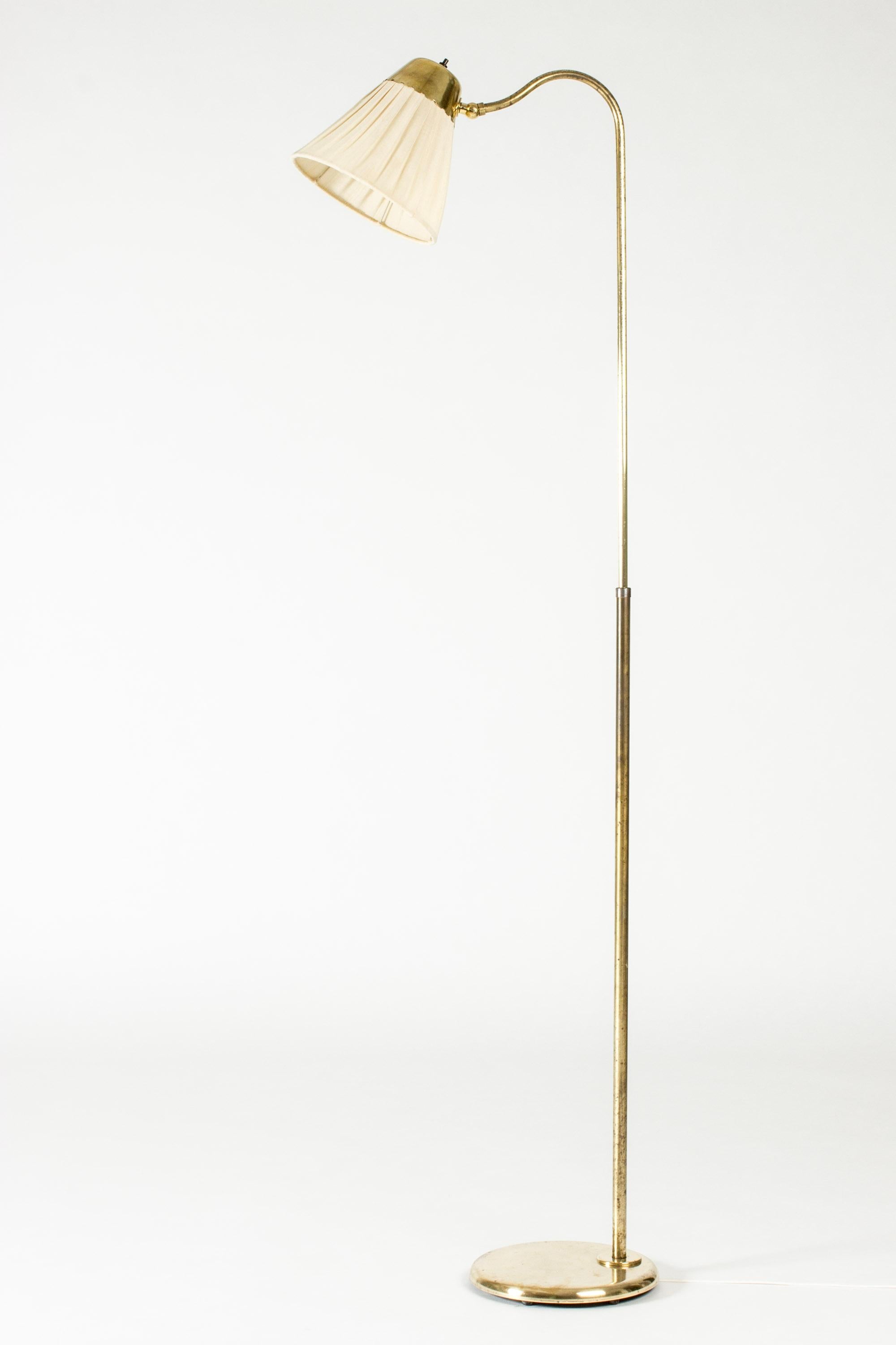 Elegant lampadaire de Böhlmarks, en laiton avec un abat-jour original tapissé de lin. Bordure festonnée décorative sur la partie en laiton de l'abat-jour. Hauteur réglable.