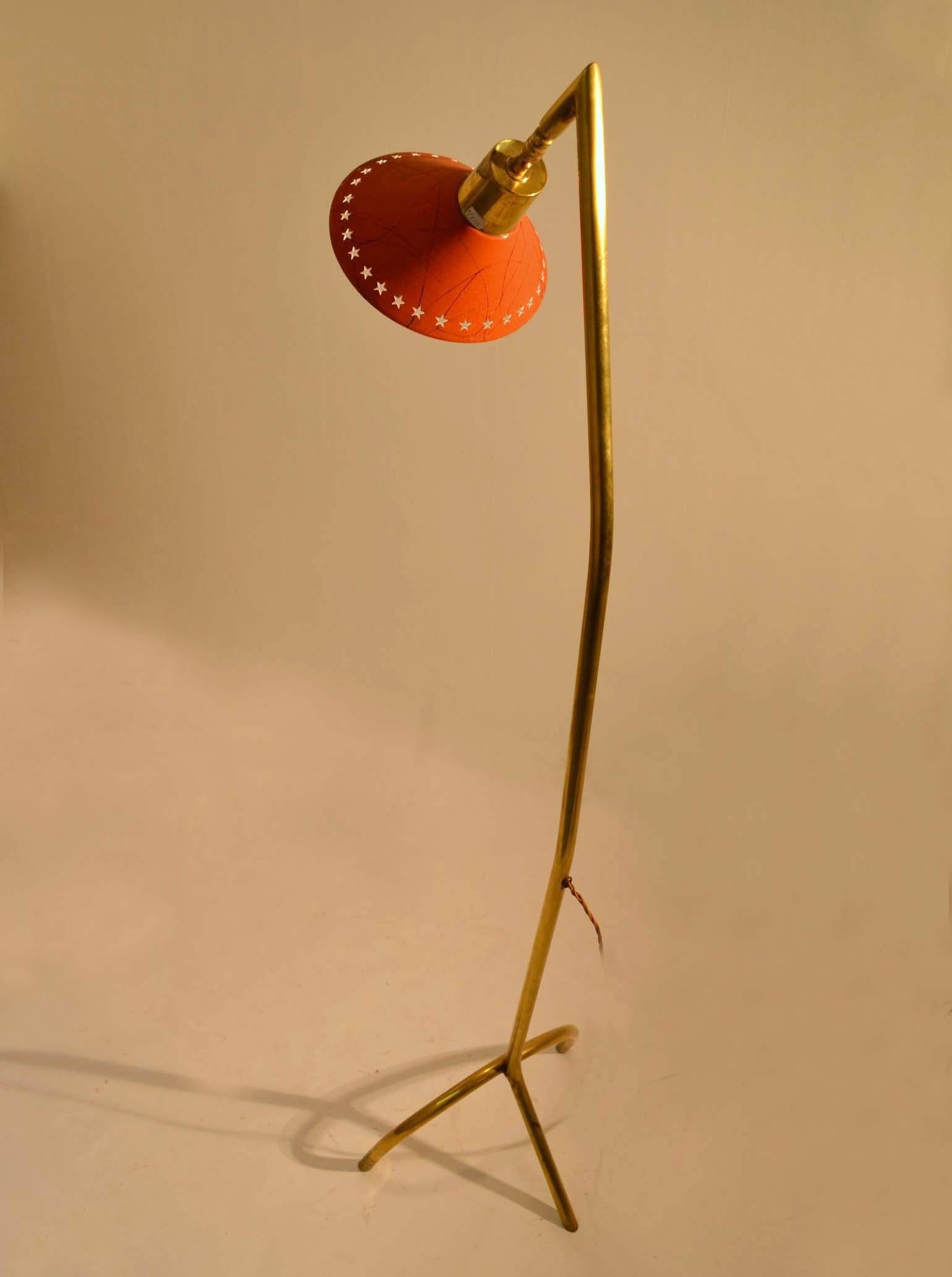 Mid-Century Modern brass floor lamp on tripod leg with adjustable orange enameled shade is perfect for reading with directed light. The legs are weighted inside the tubes for extra balance.
The shade has an array of perforated stars and a swirl line