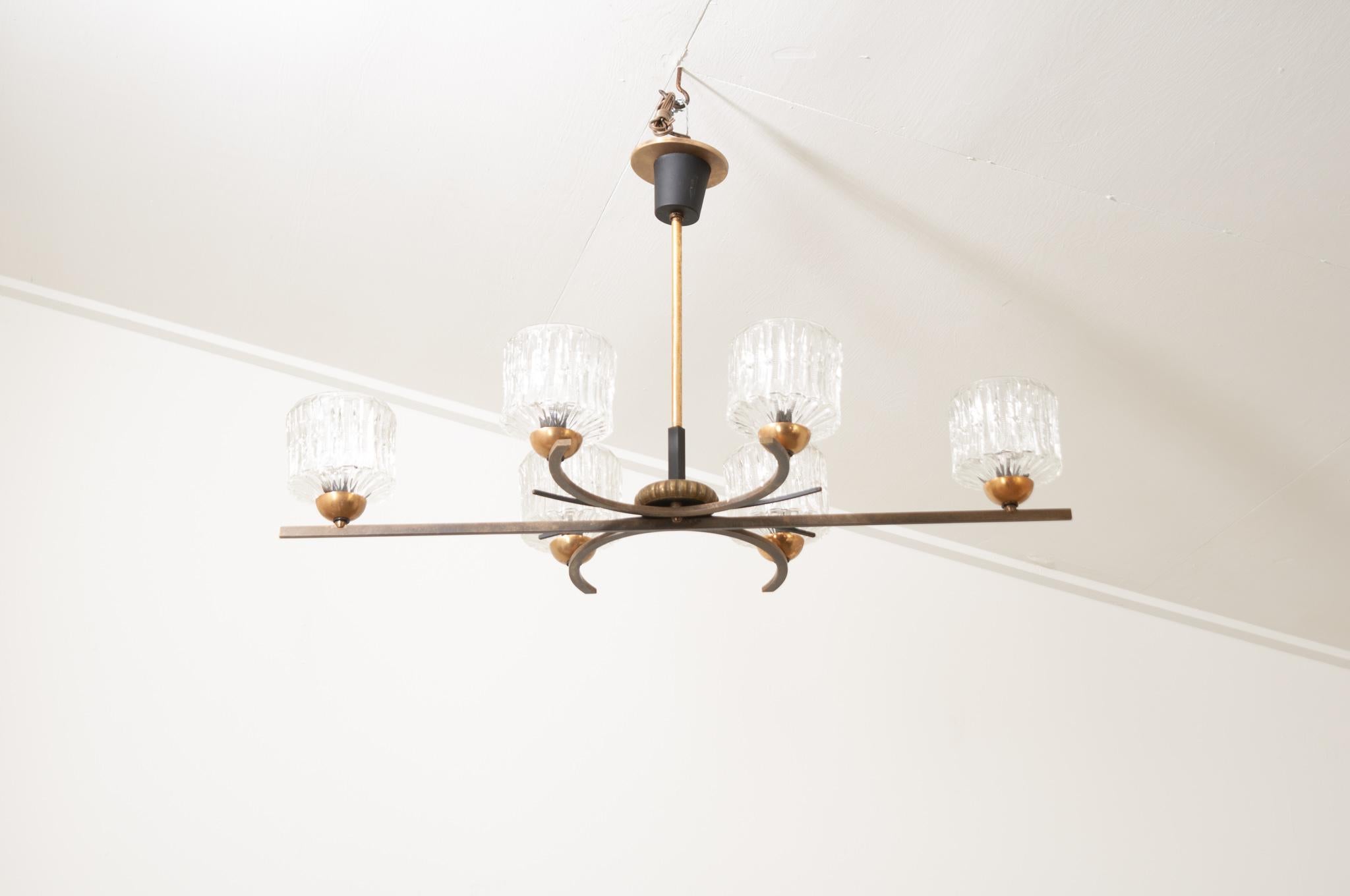 The Mid-Century Modern flush mount chandelier from France is in wonderful condition. A center, horizontal bar runs across the fixture and is flanked by two C shaped designs. The whole fixture holds 6 candles all with pattern glass cups.  Recently