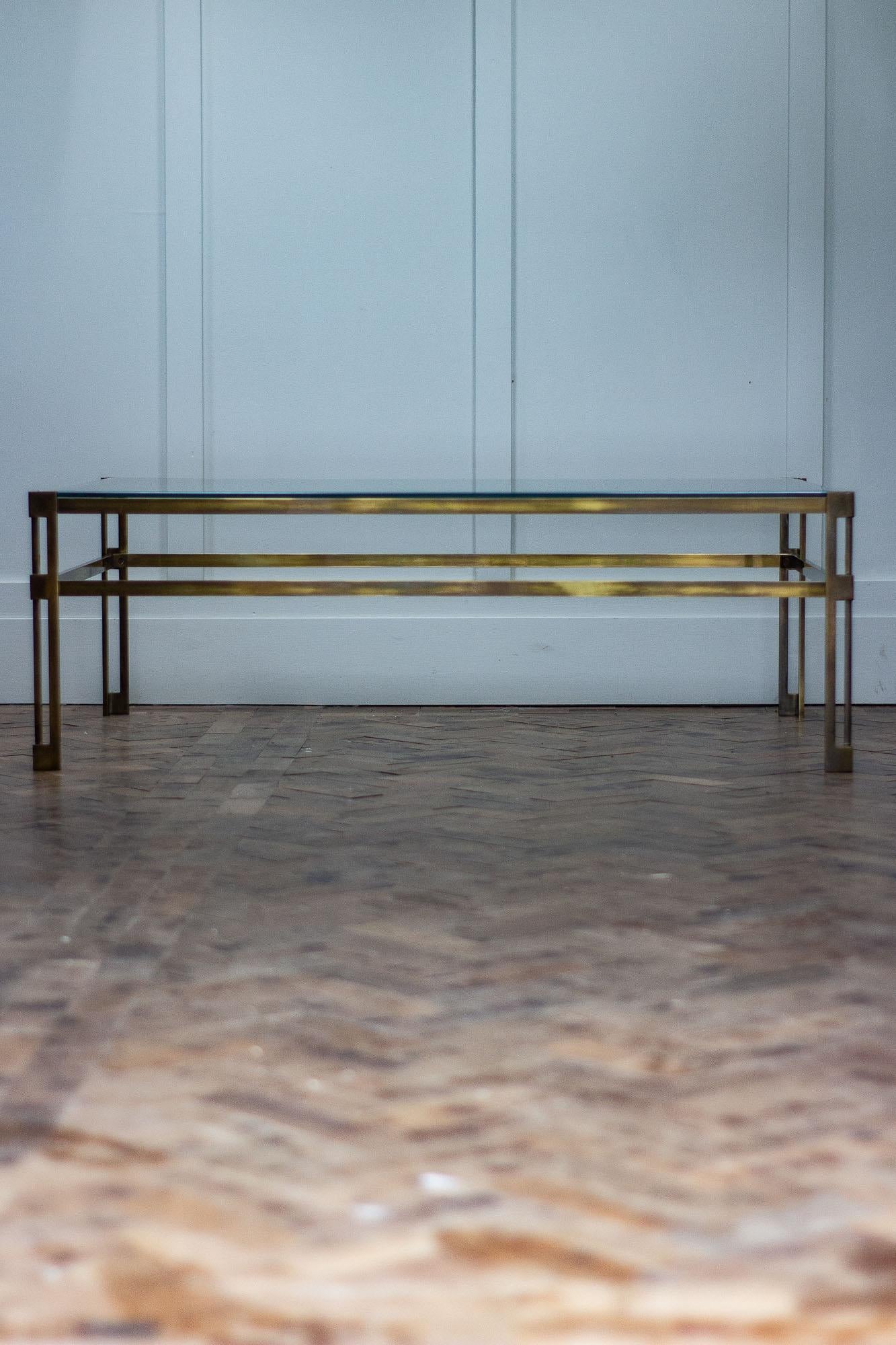 This 1970s Mid-Century Modern coffee table features solid brass legs with a tubular frame. 

The base has a geometric design to the legs. 

The table has a brand new piece of 10mm toughened glass.