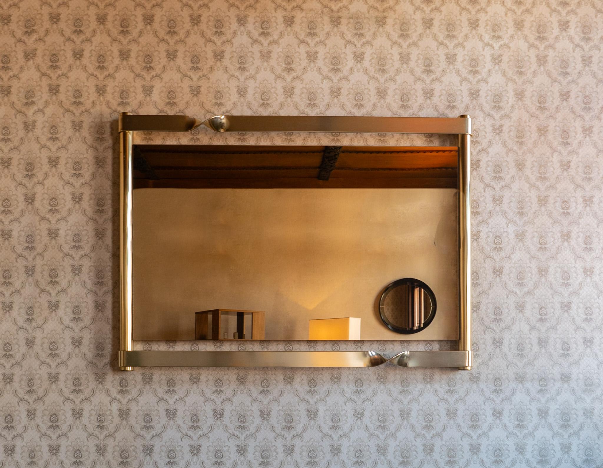 Moderner Messing-Glas-Spiegel im Stil von Luciano Frigerio, Italien 1970er Jahre.

Wir präsentieren ein atemberaubendes Schmuckstück, das Raffinesse und Eleganz ausstrahlt - ein großes Messing  Wandspiegel mit geschwungenen Elementen und Rauchglas,