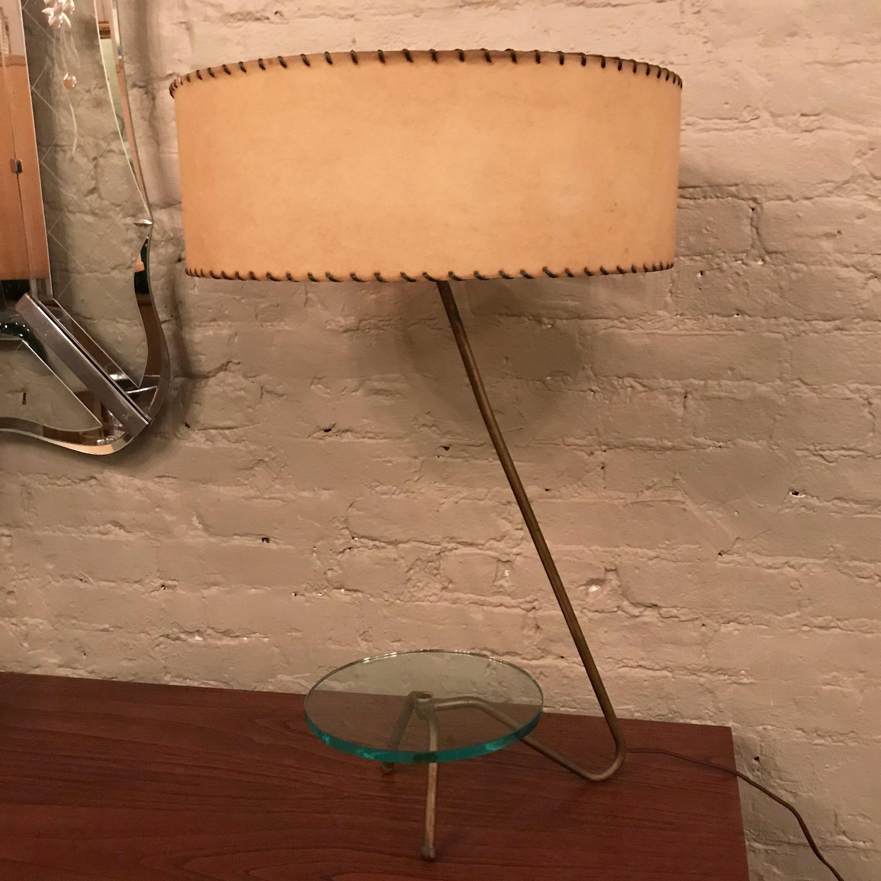 Mid-Century modern table lamp in the manner of Greta Grossman features a brass grasshopper frame with attached glass tray surface and original, stitched parchment shade. The lamp holds 2 bulbs with separate switches.

Lamp is 26.5