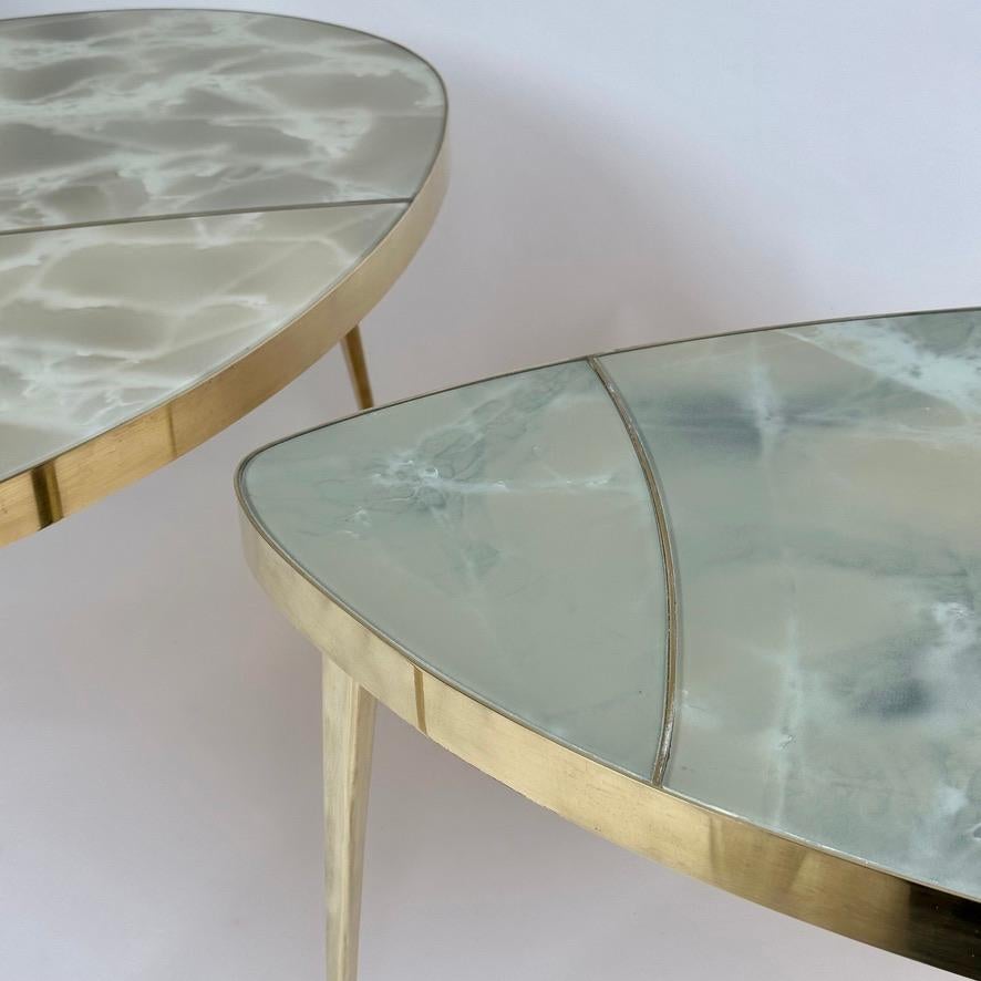 Cet ensemble de trois tables basses peut être présenté de plusieurs manières dans n'importe quel contexte moderne. Les plateaux en verre d'art Murano vert (avec un effet pierre) et les détails en laiton sont également encadrés de laiton. Cet