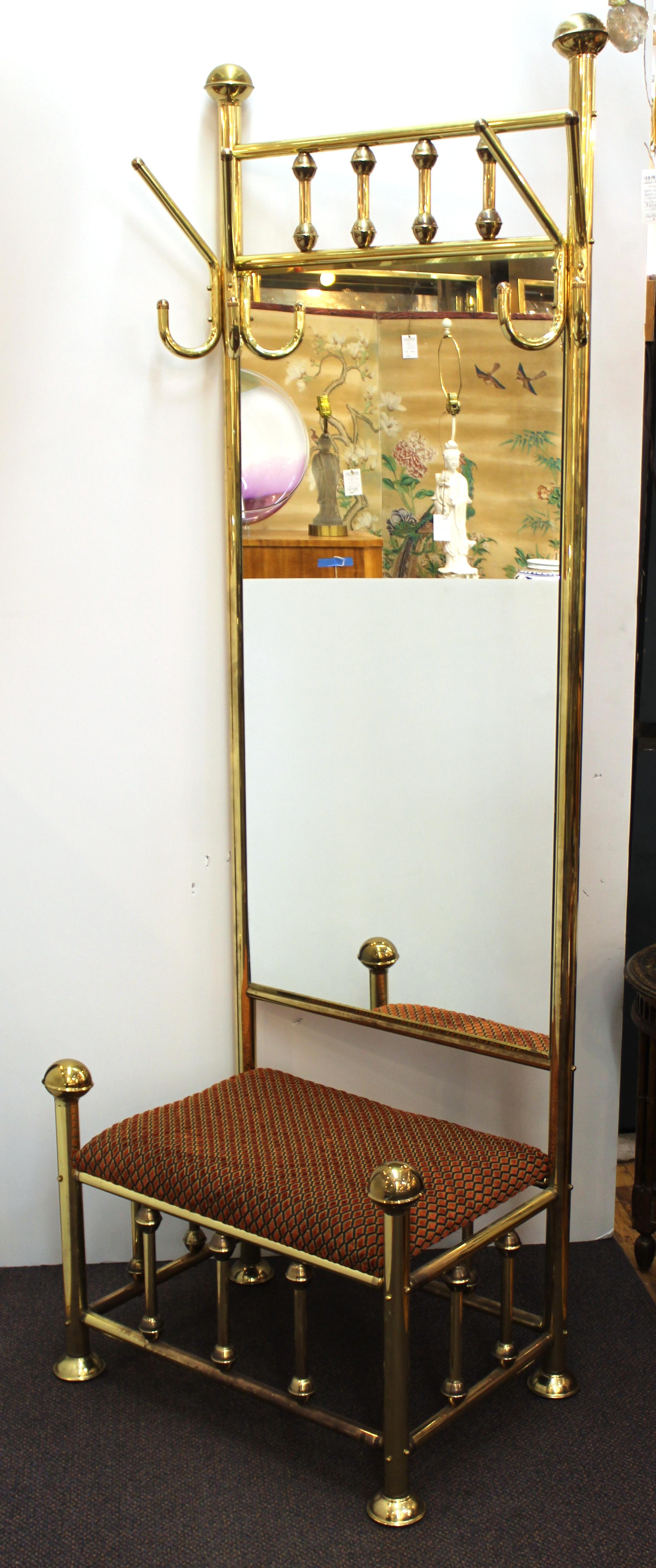 Mid-Century Modern brass hall tree with tall mirror and upholstered bench. The piece has hooks on both sides of the upper part and has recently been reupholstered. In great vintage condition with minor age-appropriate wear to the metal surfaces.