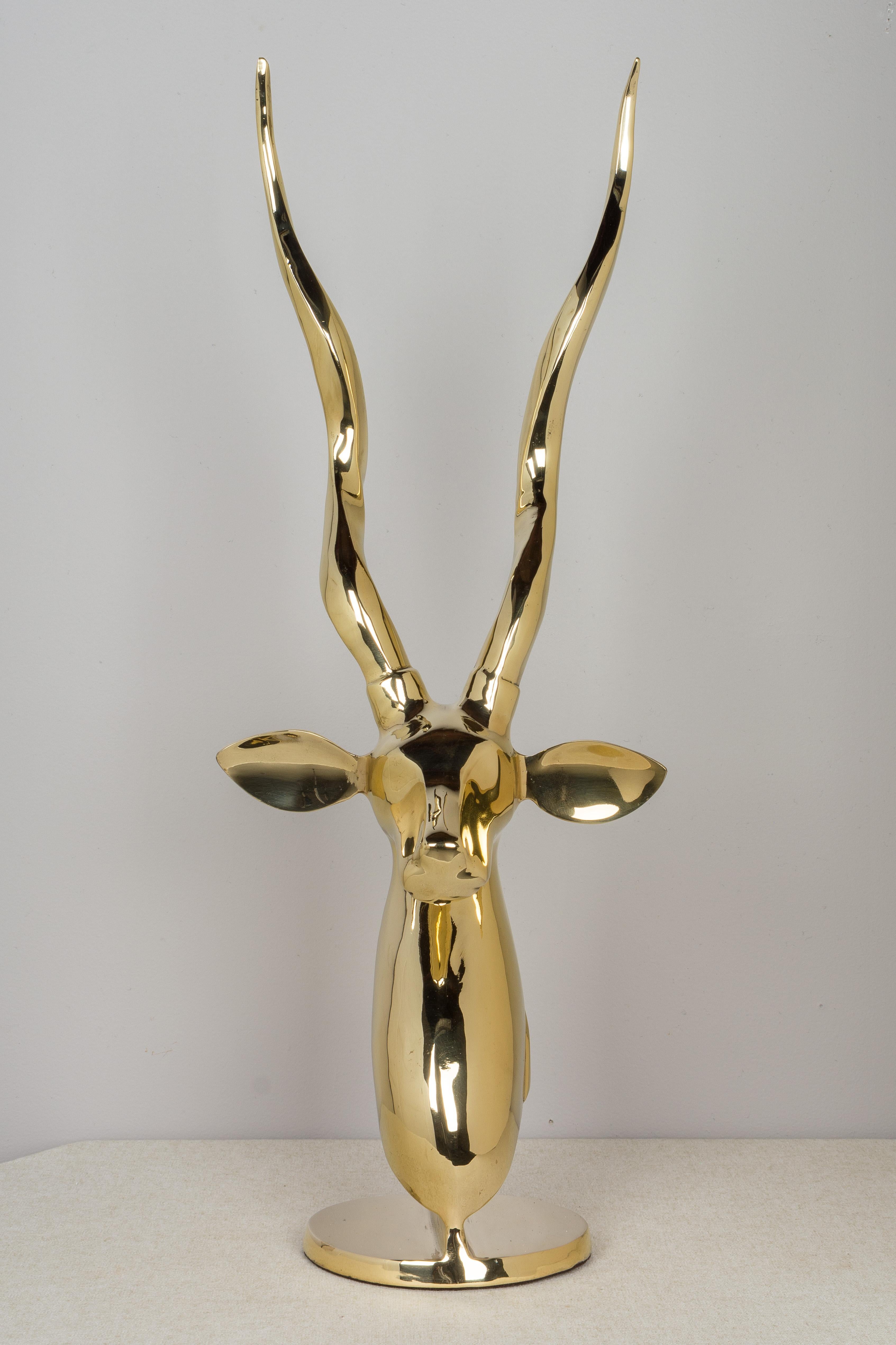 A Mid-Century Modern polished brass sculptural bust of an African Kudo antelope, similar to a gazelle, with tall twisted horns. 
Diameter of base is 6.75