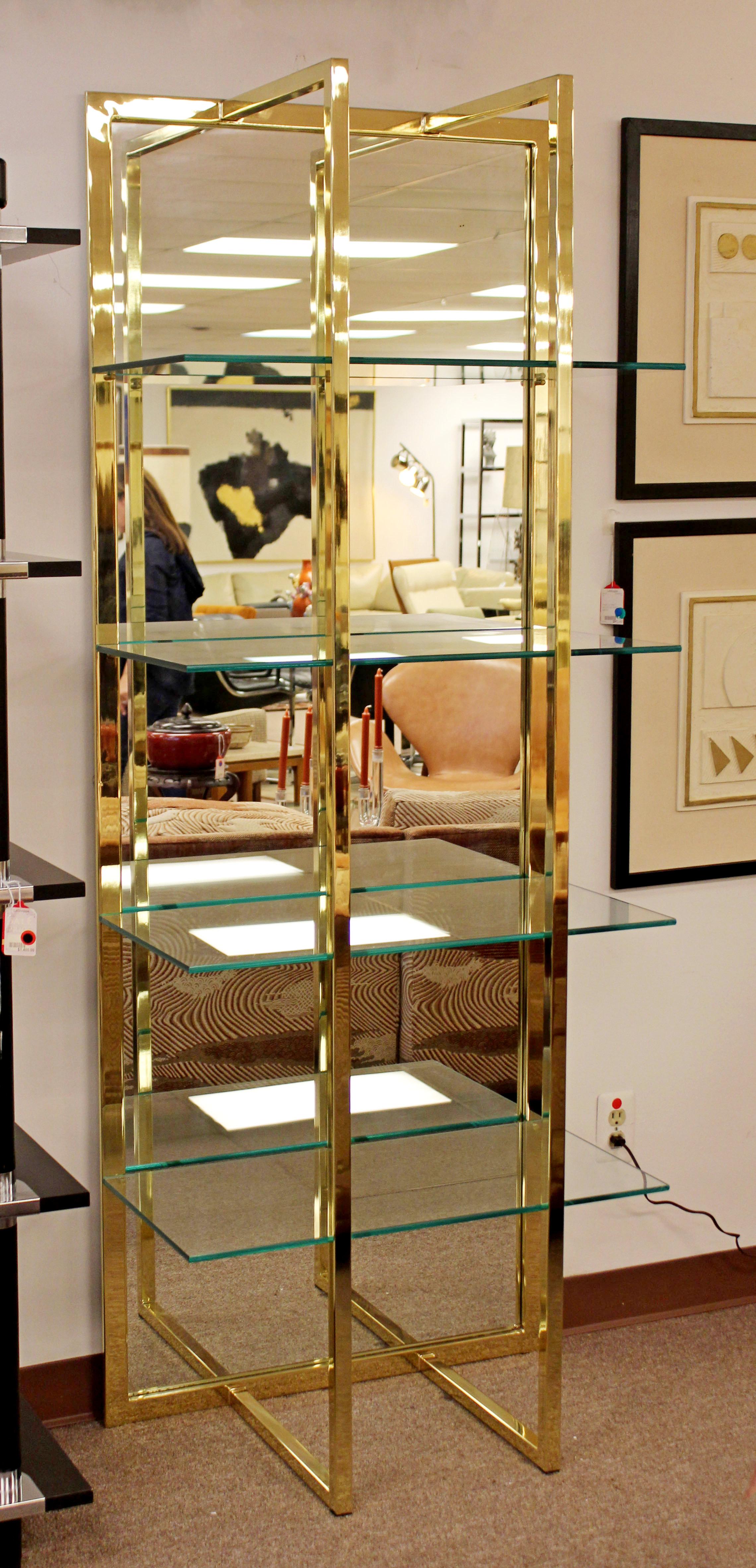 For your consideration is a magnificent shelving unit, with a brass case, mirrored back and four glass shelves, in the style of Milo Baughman, circa the 1970s. In excellent condition. The dimensions are 30