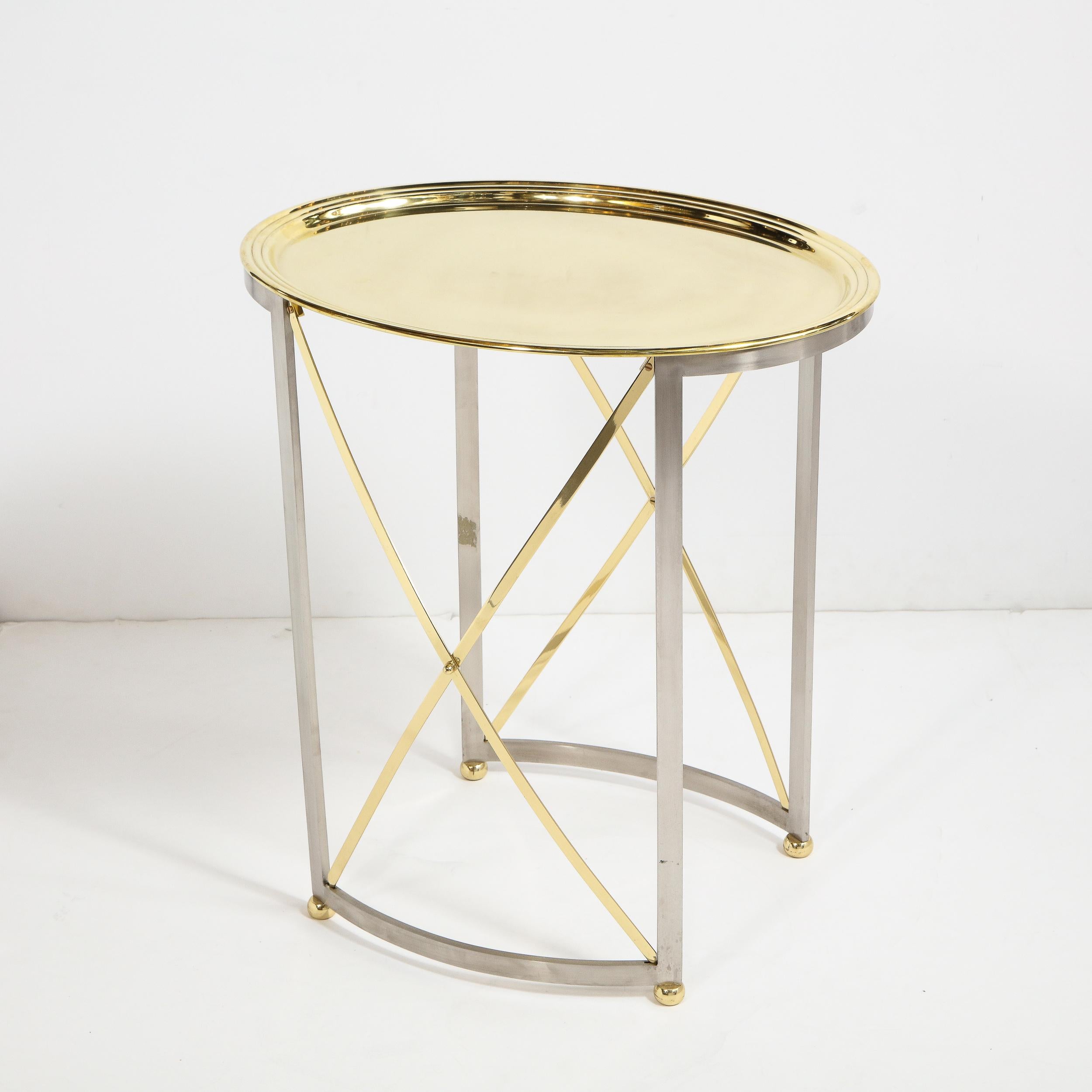 This chic and bold Mid-Century Modern occasional/ side table was realized in France, circa 1980 by the celebrated maker Maison Jansen. It features two brushed nickel legs on each side connected a curved concave band at the bottom and X-form brass