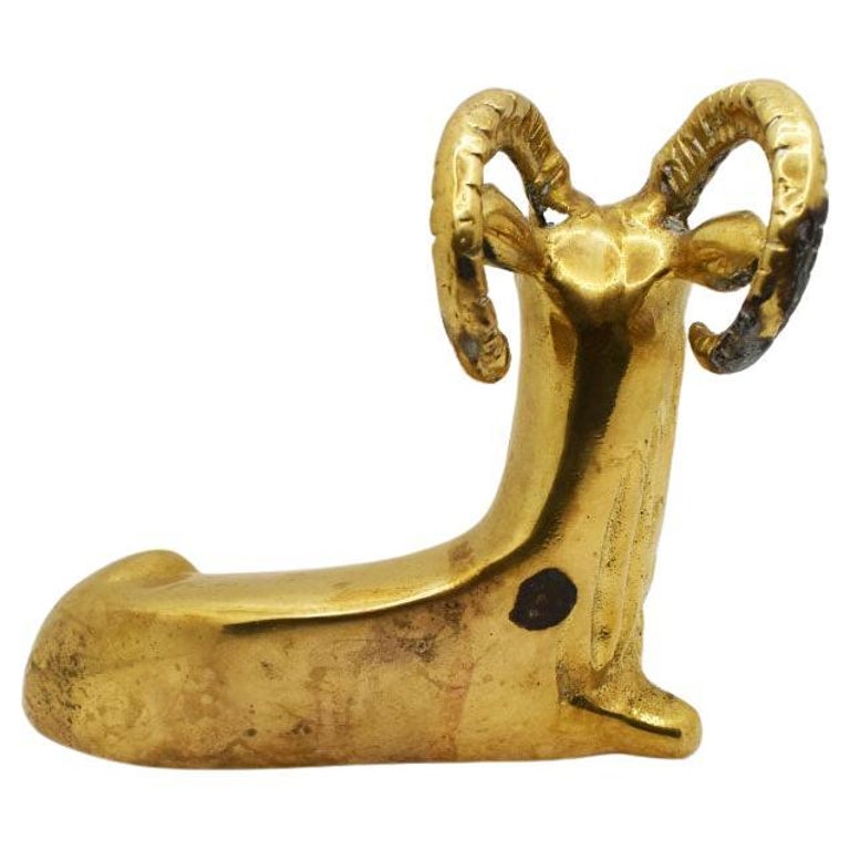 A small brass sculpture of a ram. This mid-century beauty will be perfect if styled on a bookshelf. It features a ram with its horns curled backward. He is seated with his legs curled underneath. 

Dimensions:
5