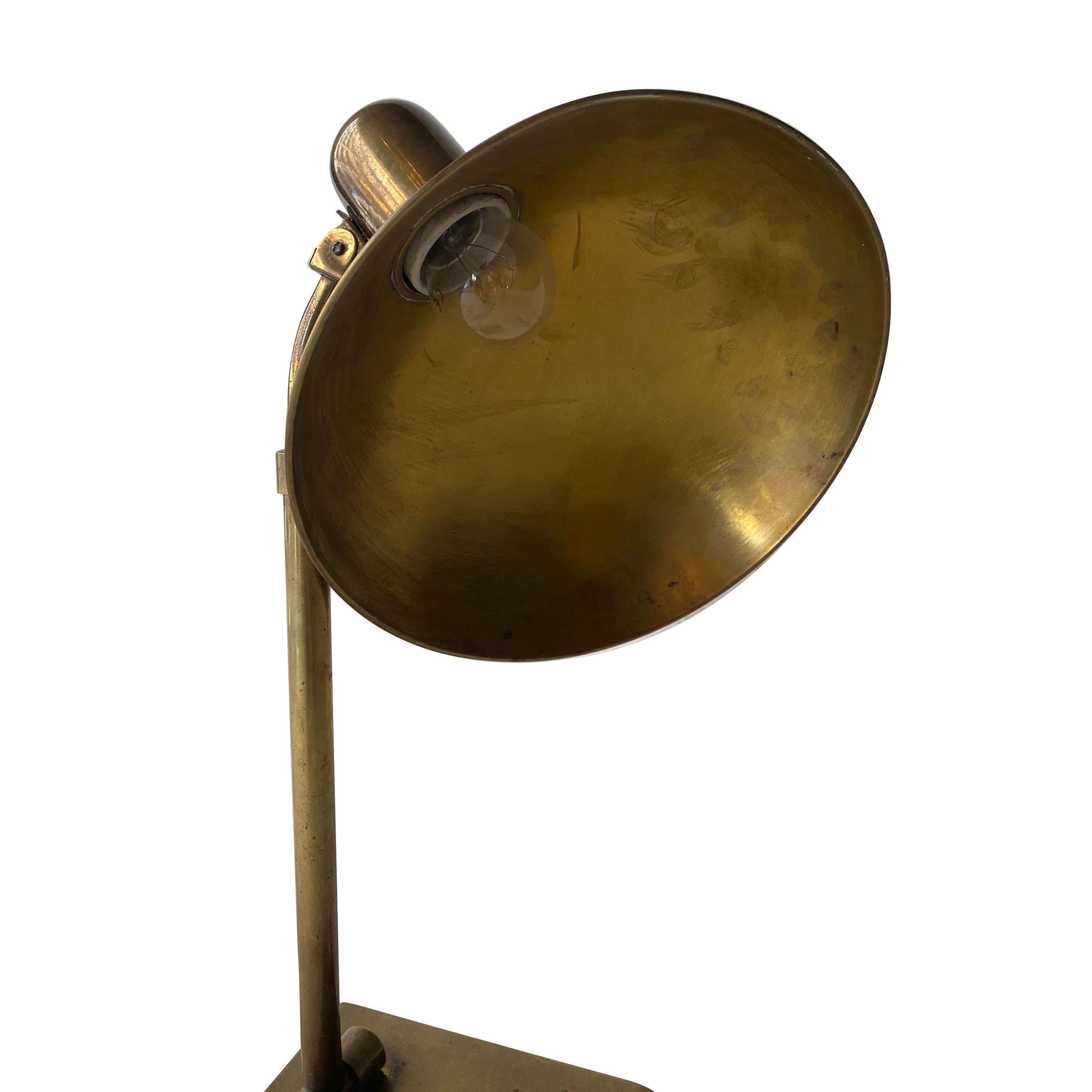 Brass regulable table lamp with a circular screen and button to turn it on and off.