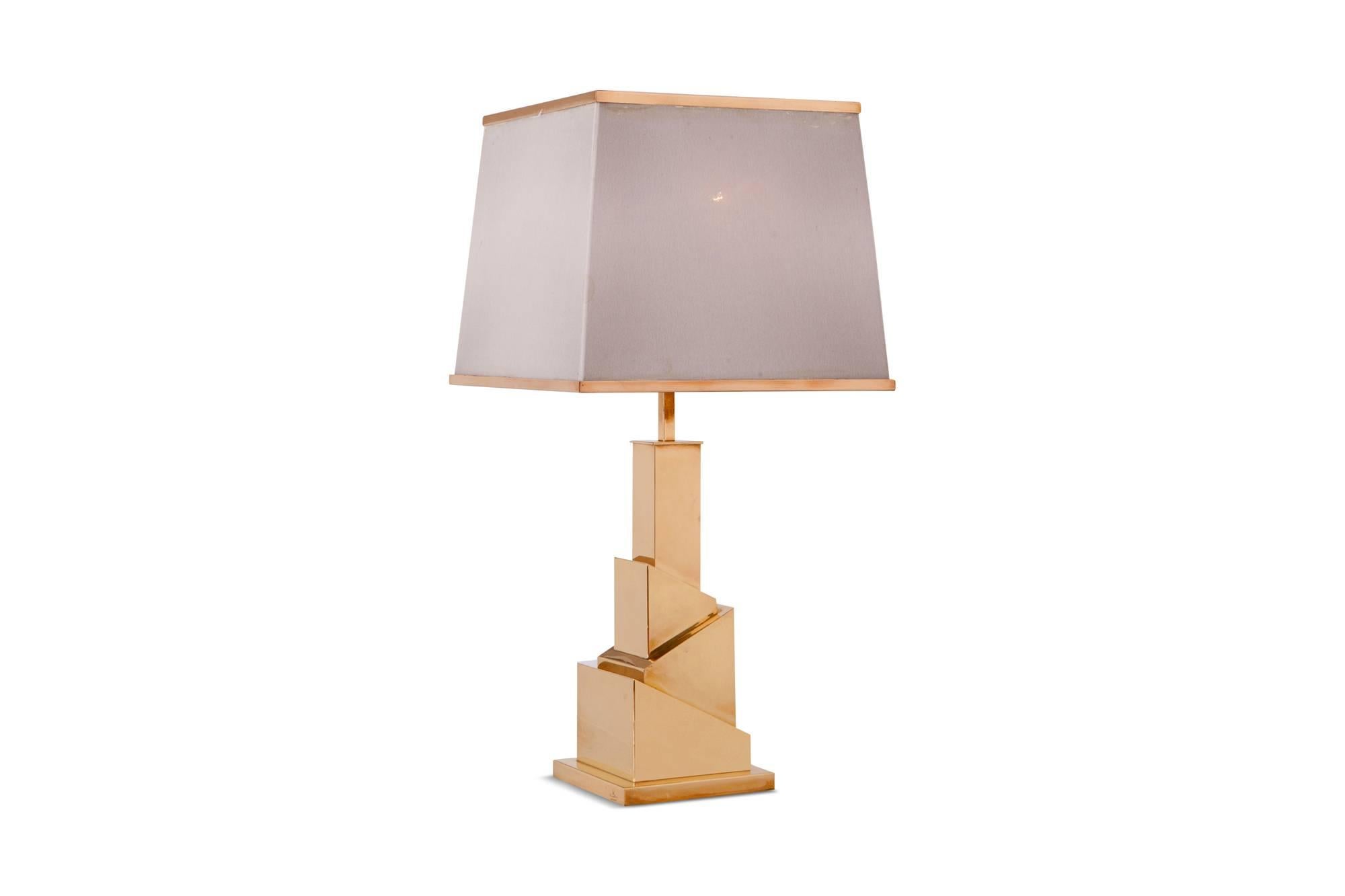 Hollywood Regency rare cubist shaped table lamp in brass by the master Romeo Rega.
The lamp is provided with two lamp fittings, covered by a crème colored linen shade to create a nice light partition. The shade is also finished with brass