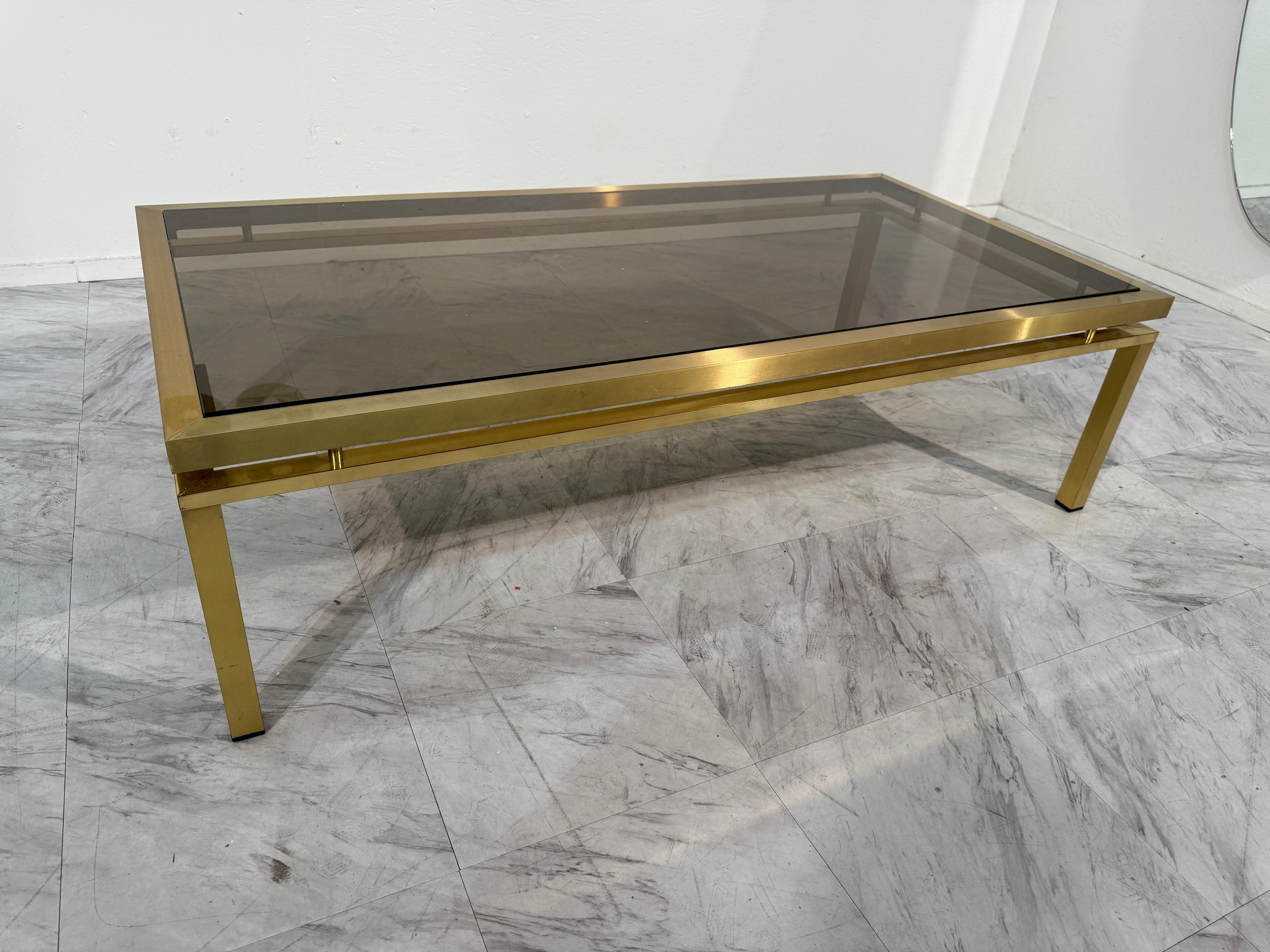 Elegante tavolino rettangolare di metà secolo moderno degli anni '70, caratterizzato da una struttura in ottone lucido abbinata a un piano in vetro fumé. Le linee minimaliste e le superfici riflettenti conferiscono al pezzo una qualità elegante e